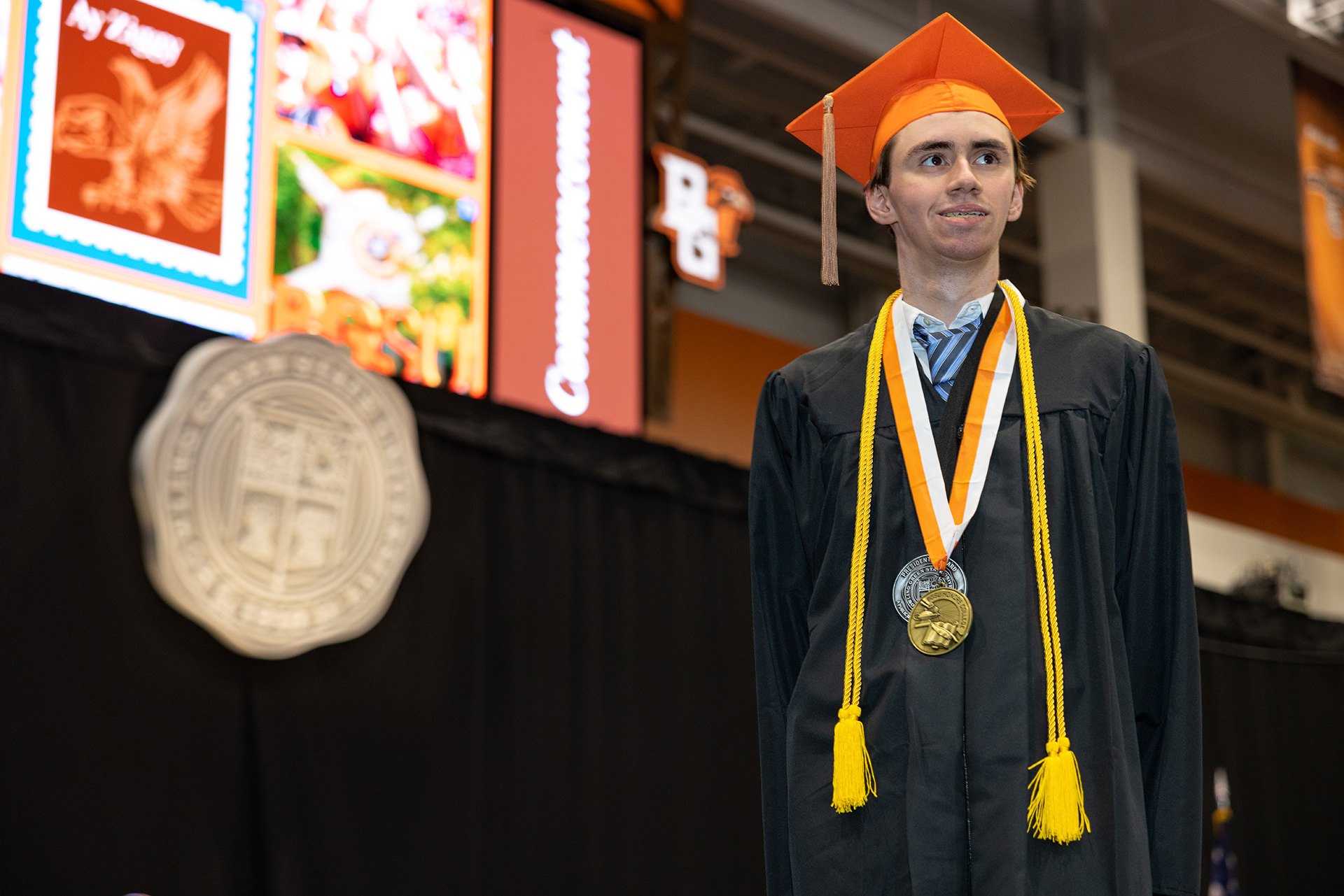 A BGSU graduate stands in front of the stage at Commencement