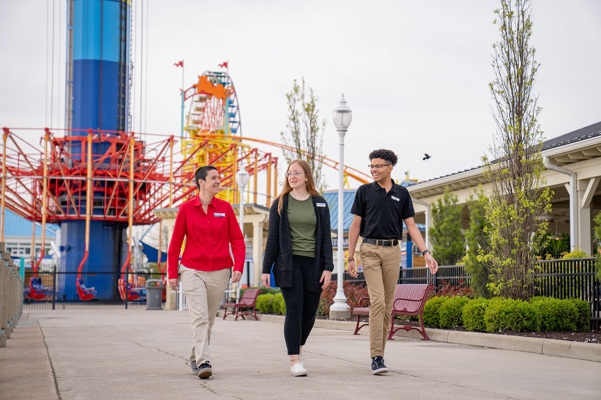 Three people walking together with roller coasters in the background