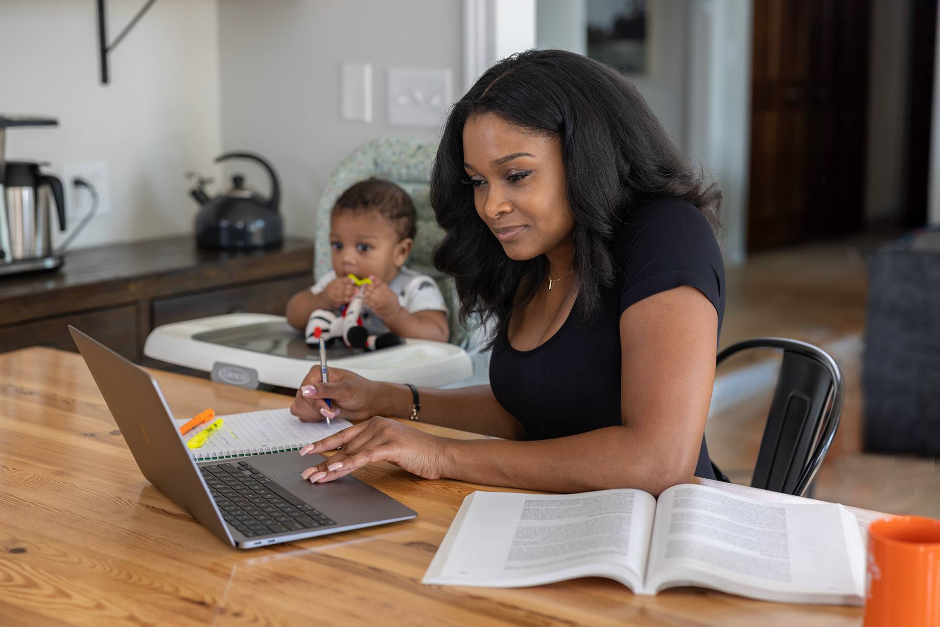 A person works on a laptop next to a young child.