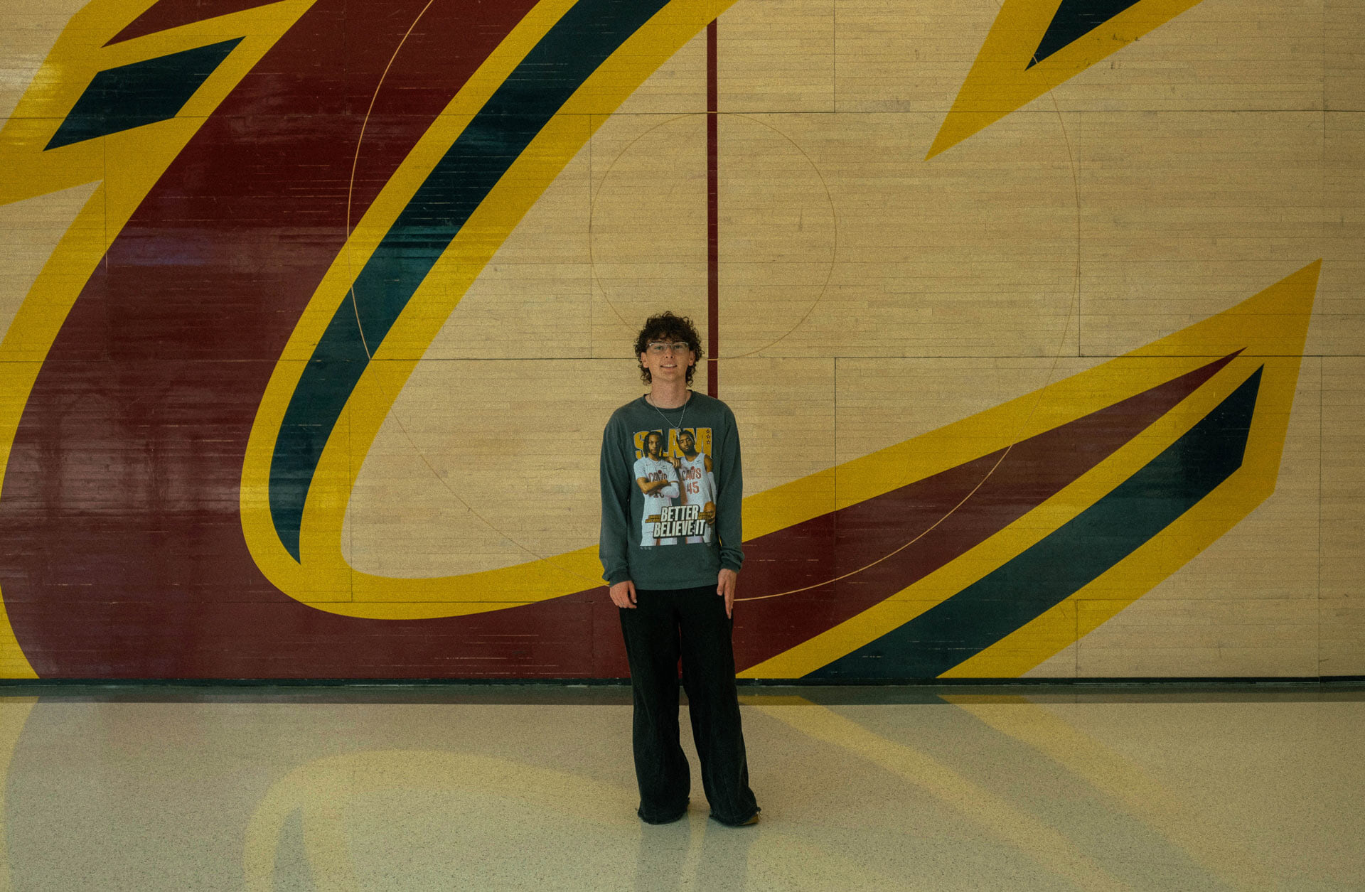 A man stands in front of a basketball court.