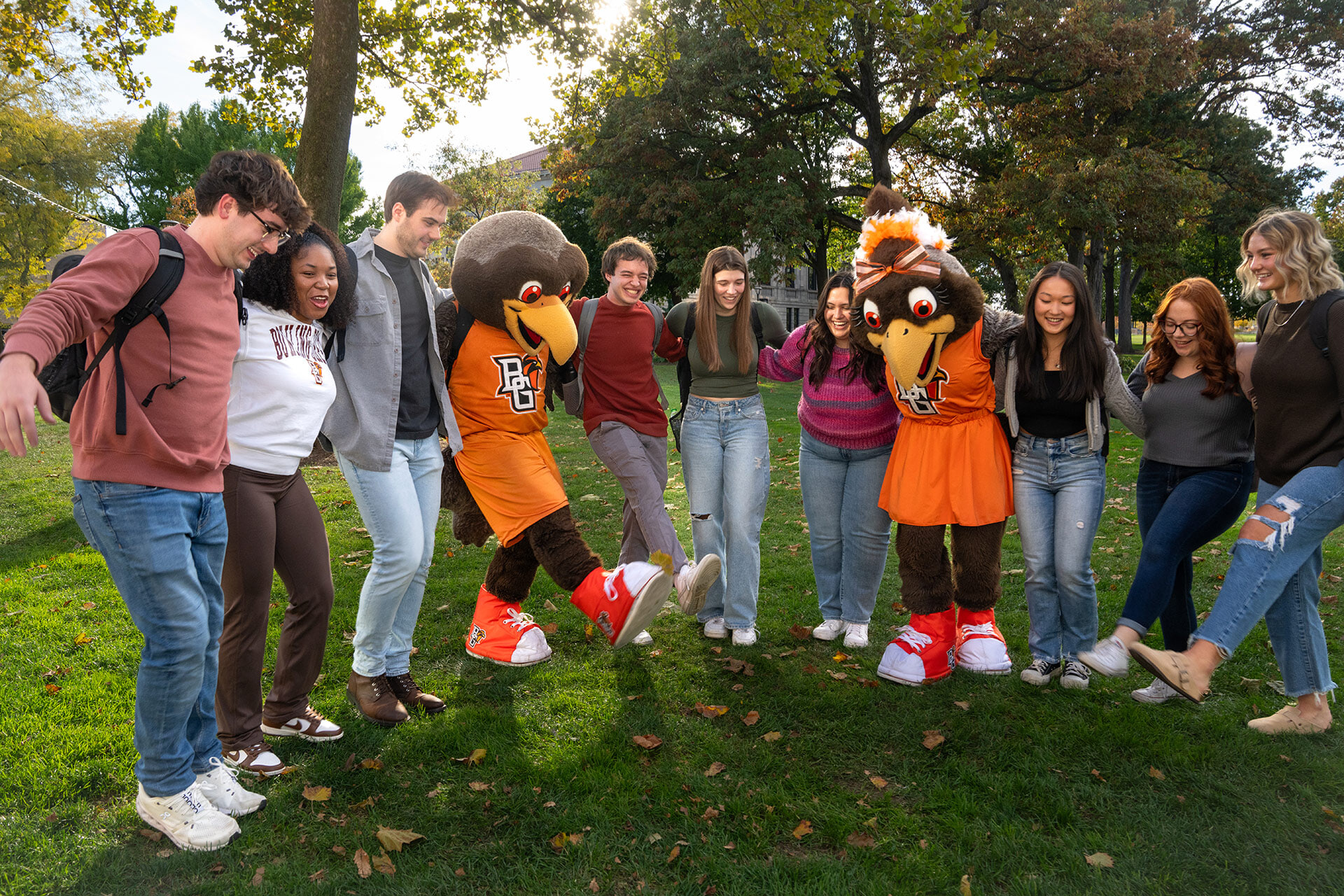 Two falcon mascots dance with a group of students