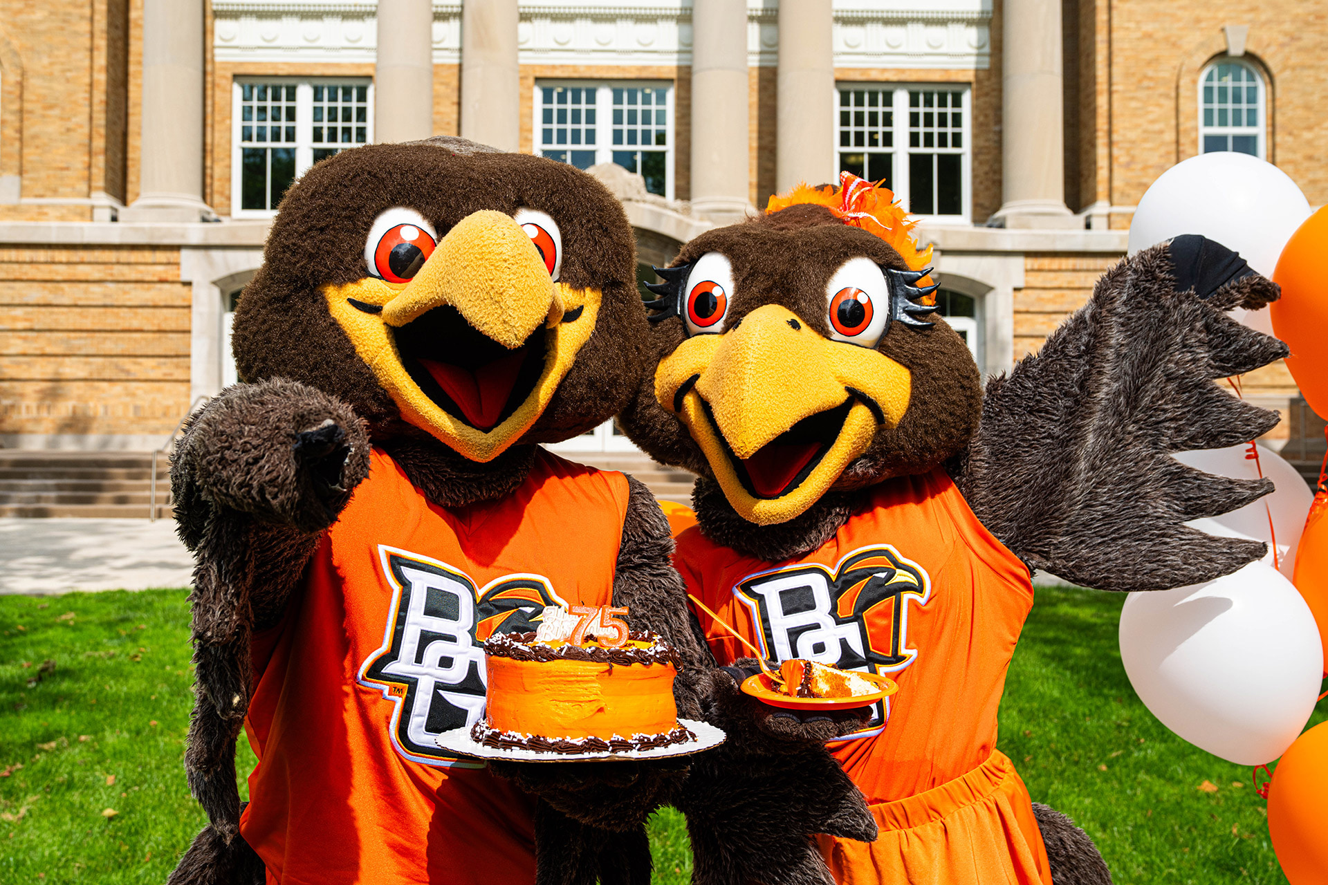 Two falcon mascots pose for a picture holding a birthday cake