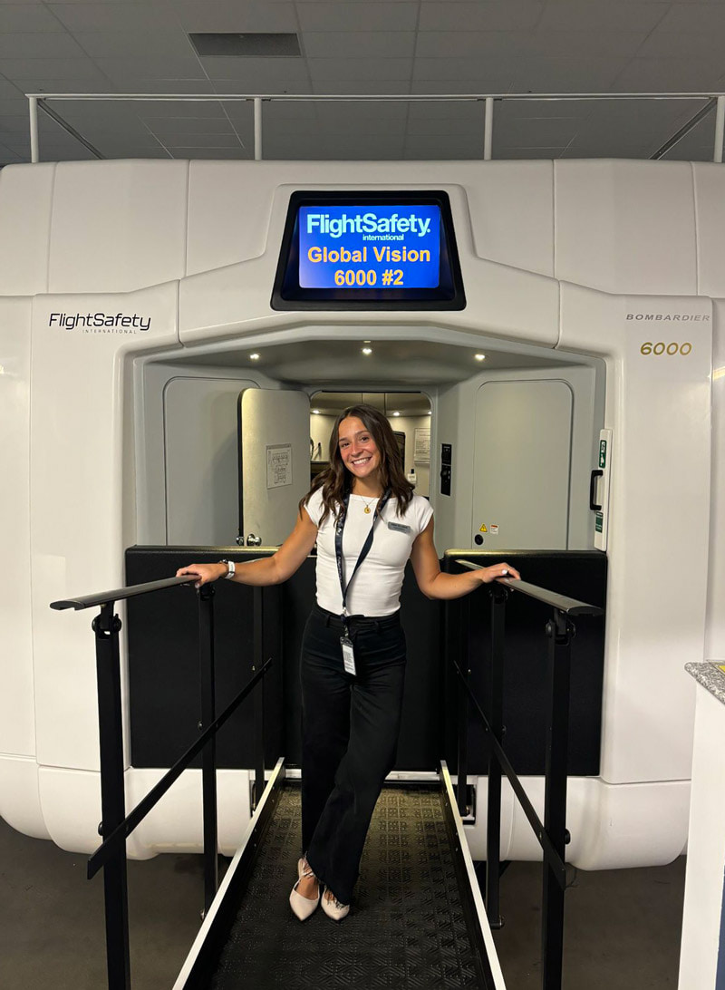 A woman poses in front a flight simulator