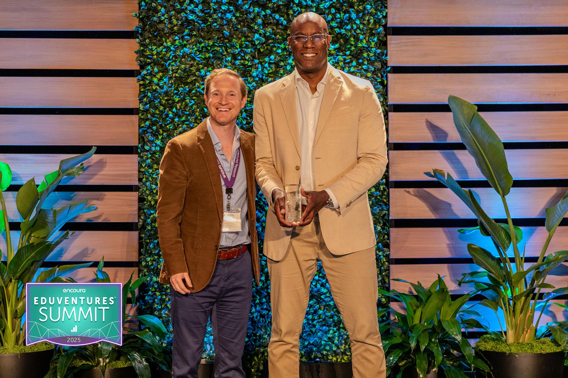 Two people stand on a stage with an award.