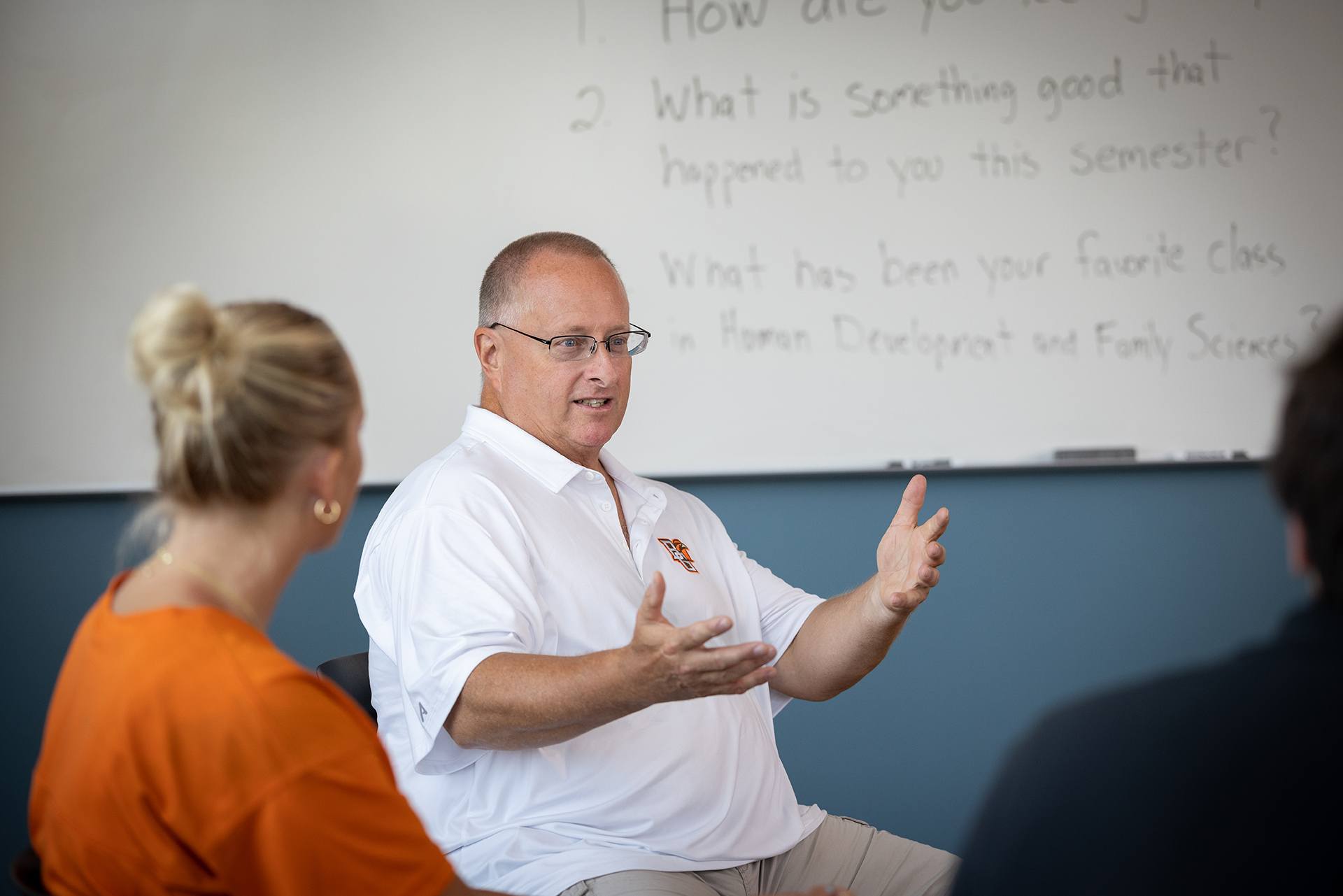 A man sits in a chair and talks to people in a group setting