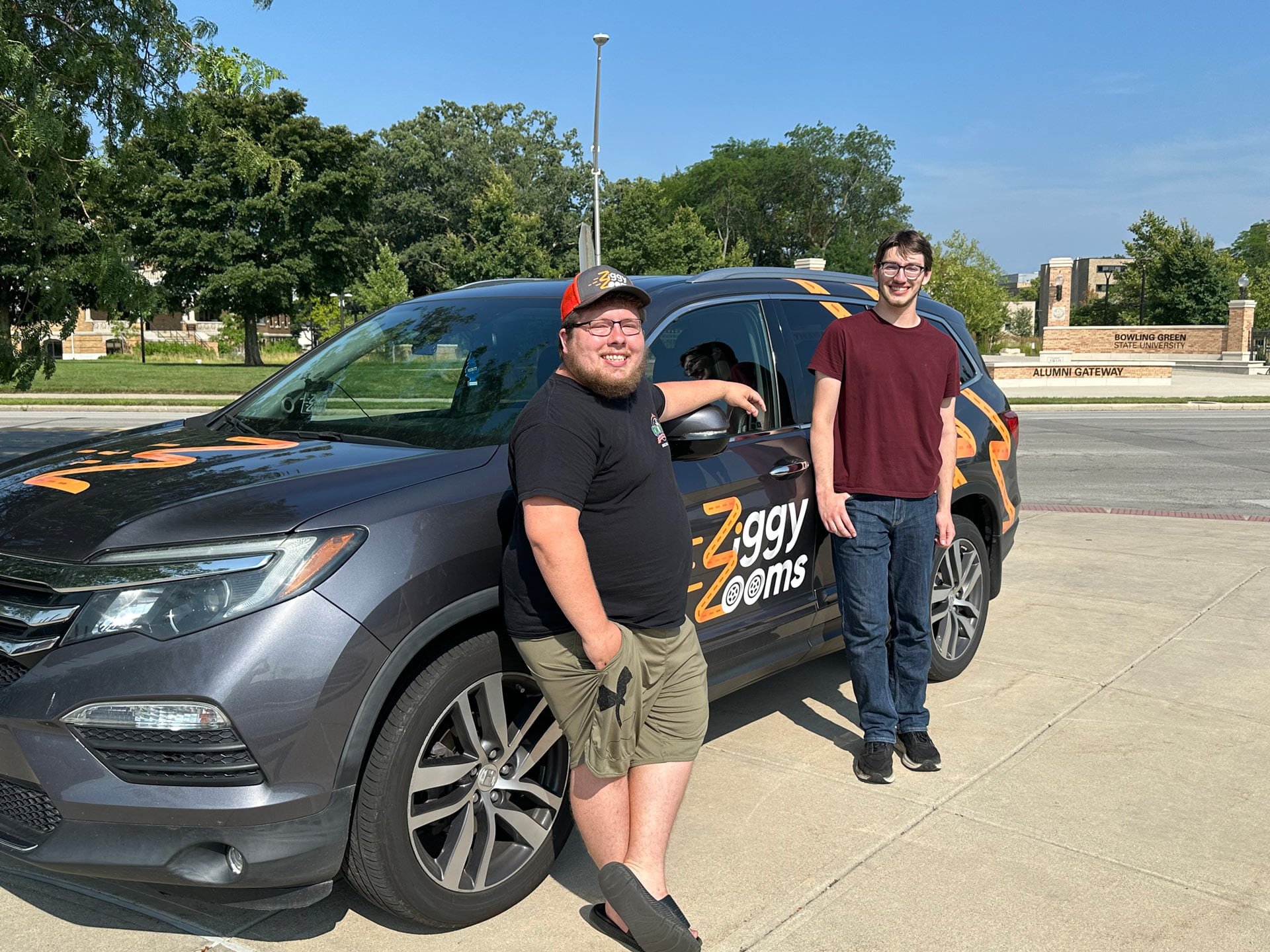 Two people stand next to a car