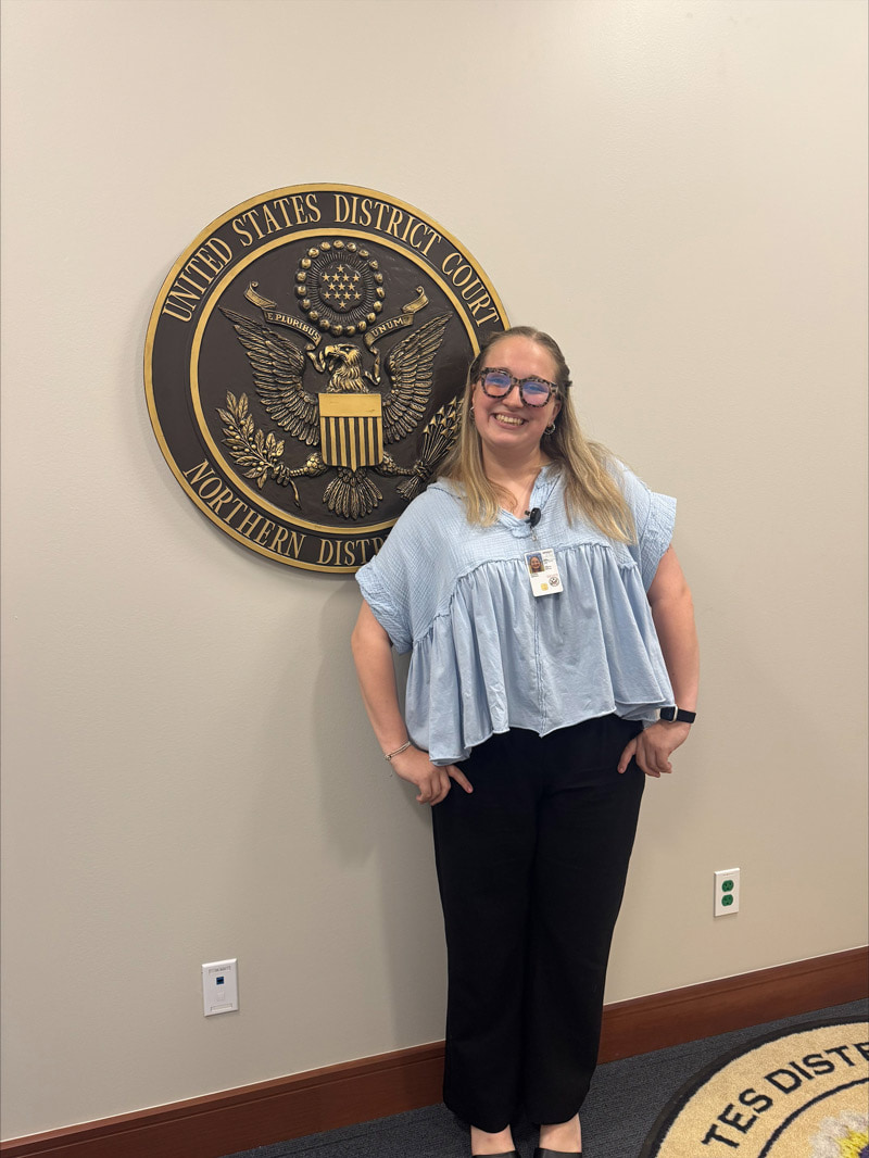 A woman stands in front of a seal inside a courtroom.