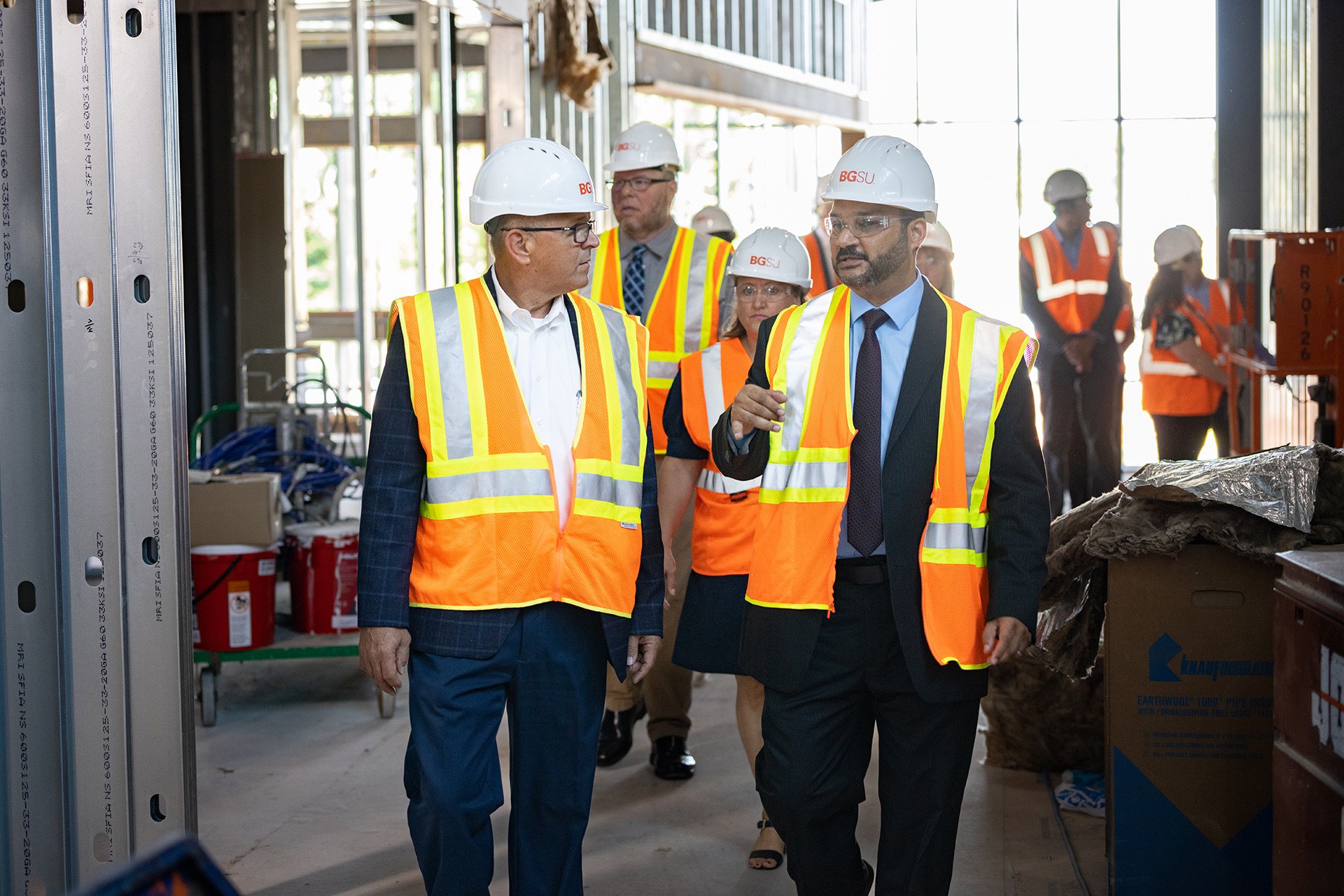People wearing hard hats and reflective vests tour the Technology Engineering Innovation Center construction