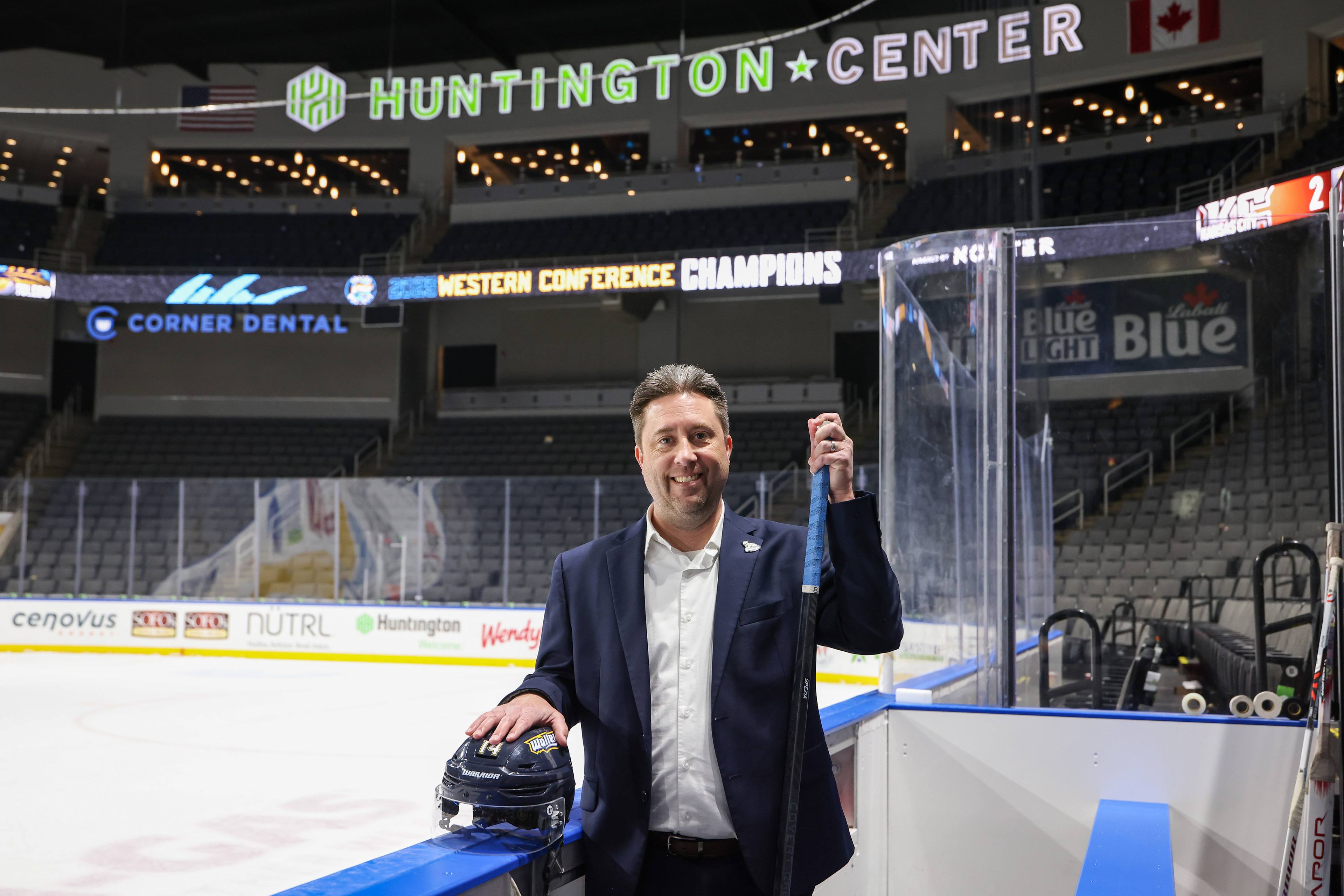 A man poses for a photo with a hockey stick.