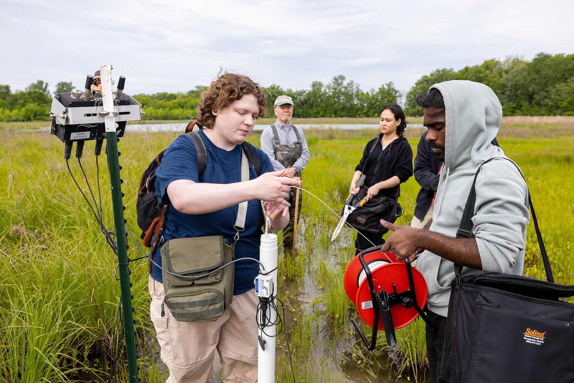 Researchers stand in a wetland collecting samples and data