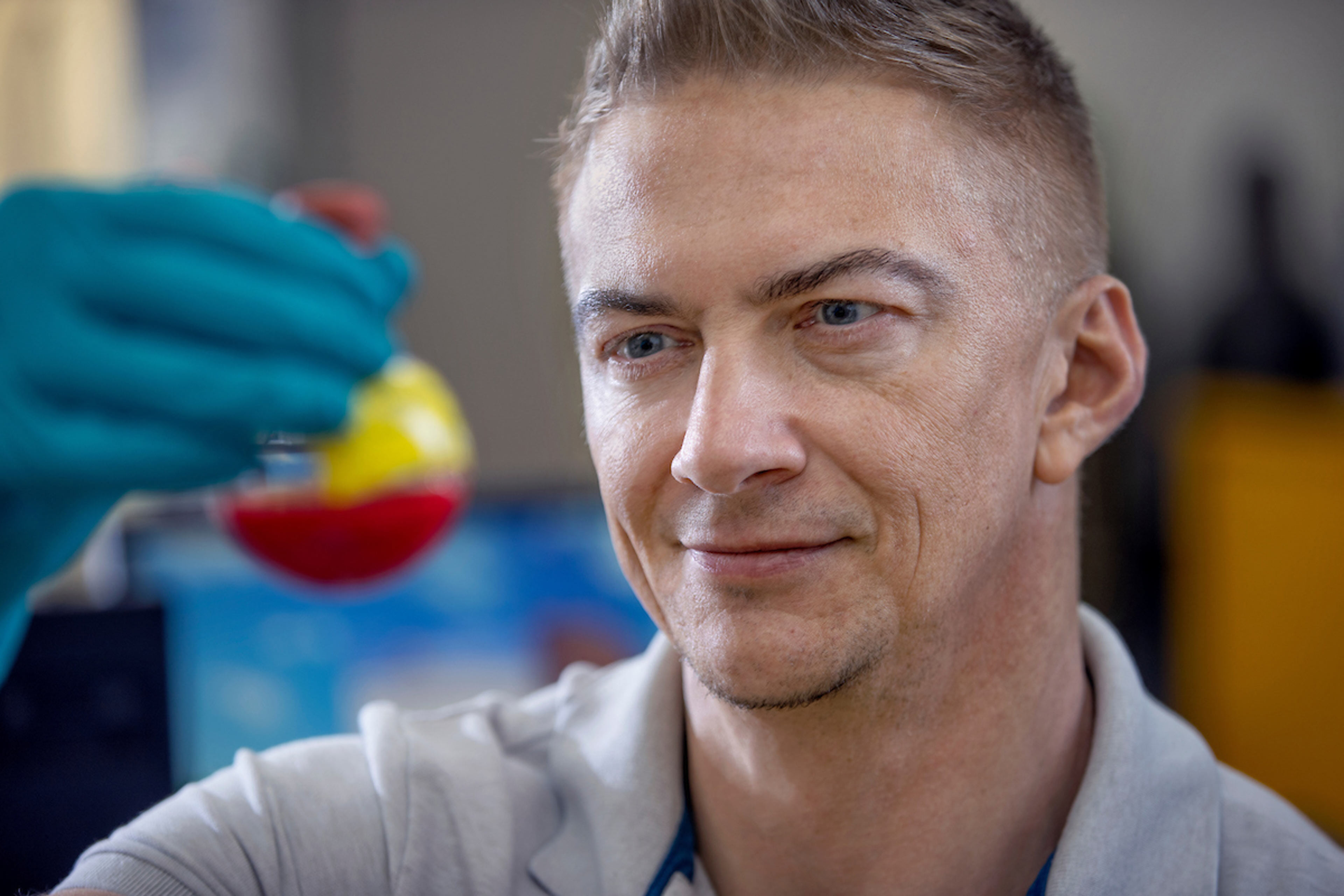 A scientist studies material inside a flask.