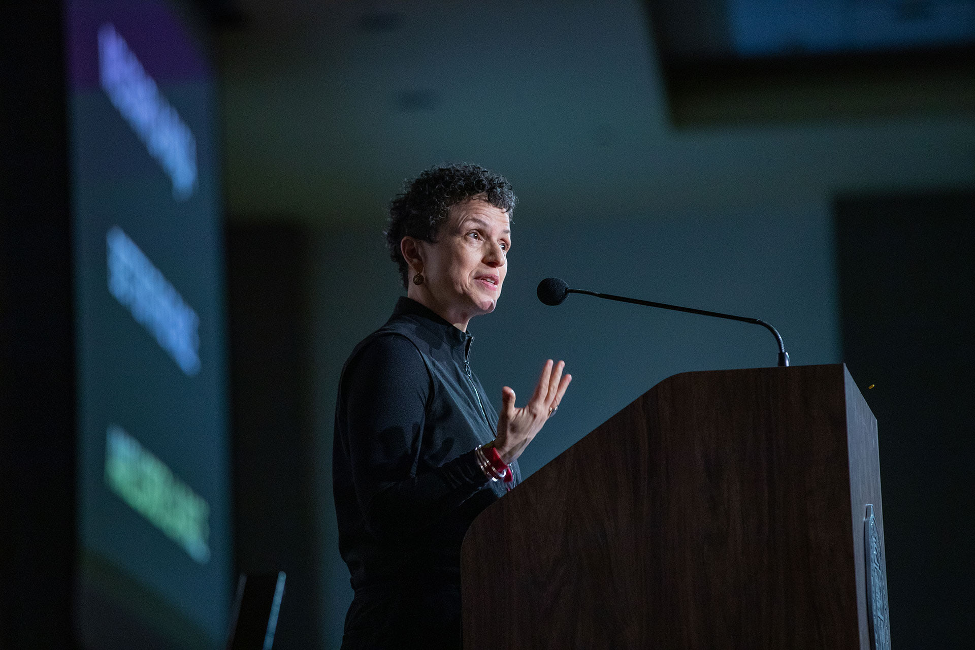 A person presents at a podium on a stage.