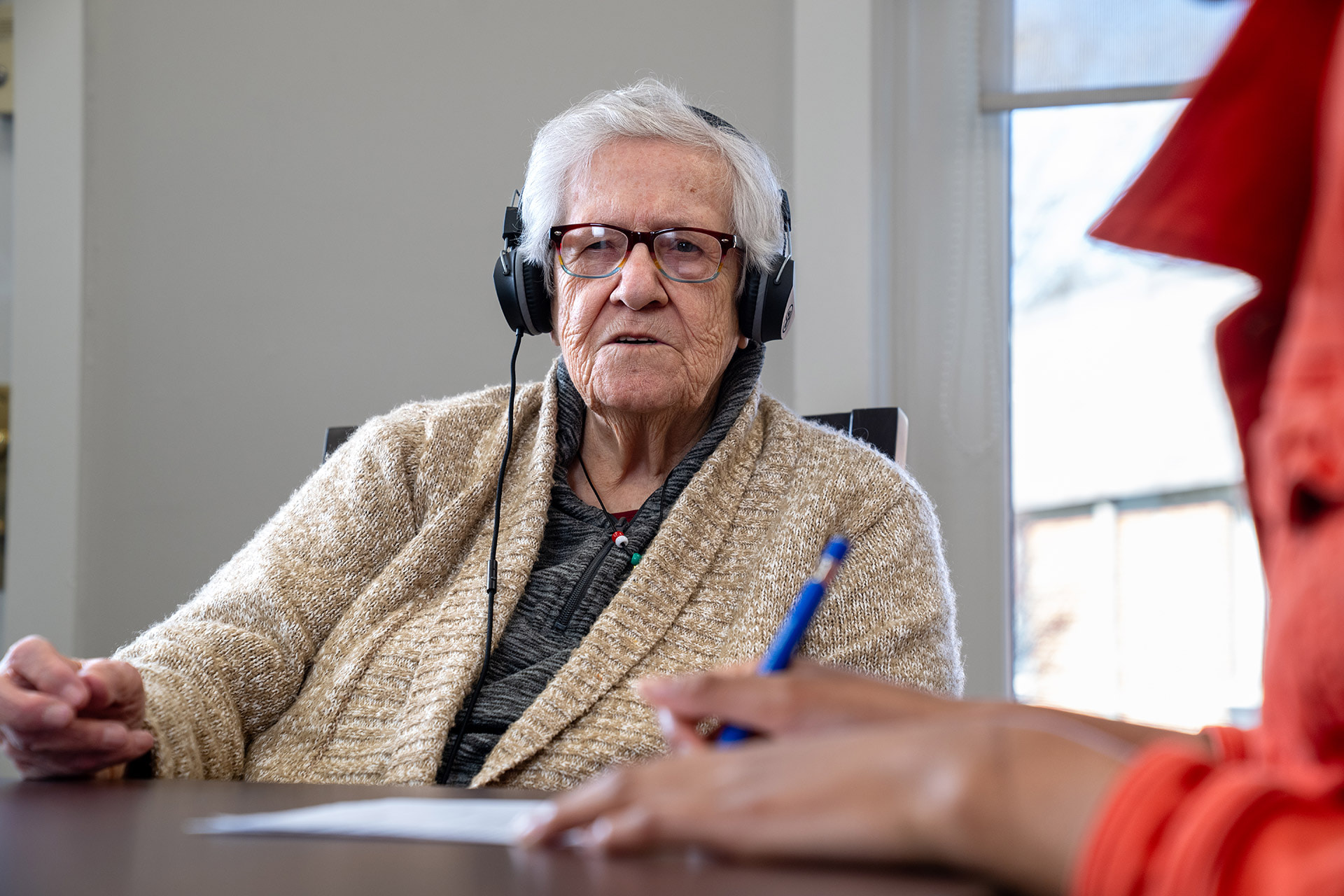 An older adult woman listens to music with headphones on.