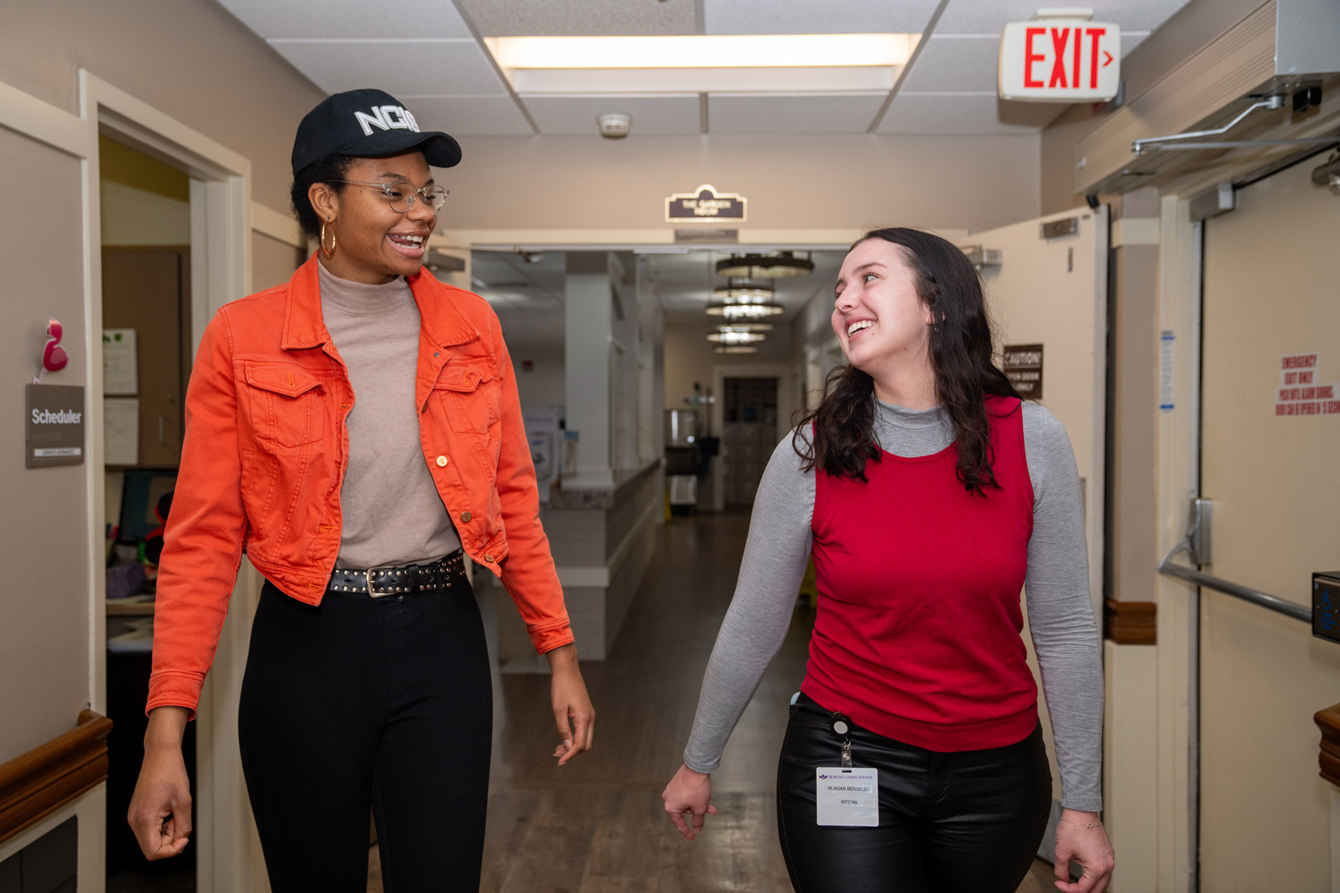 Two people walk and talk down a hallway
