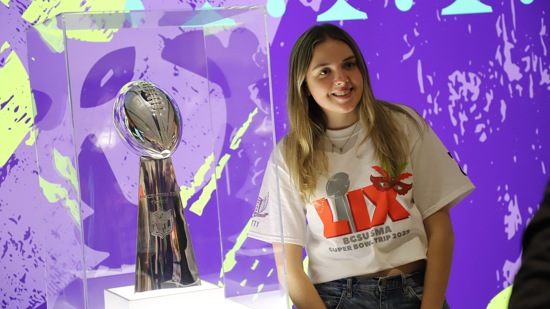 A girl stands next to a trophy.