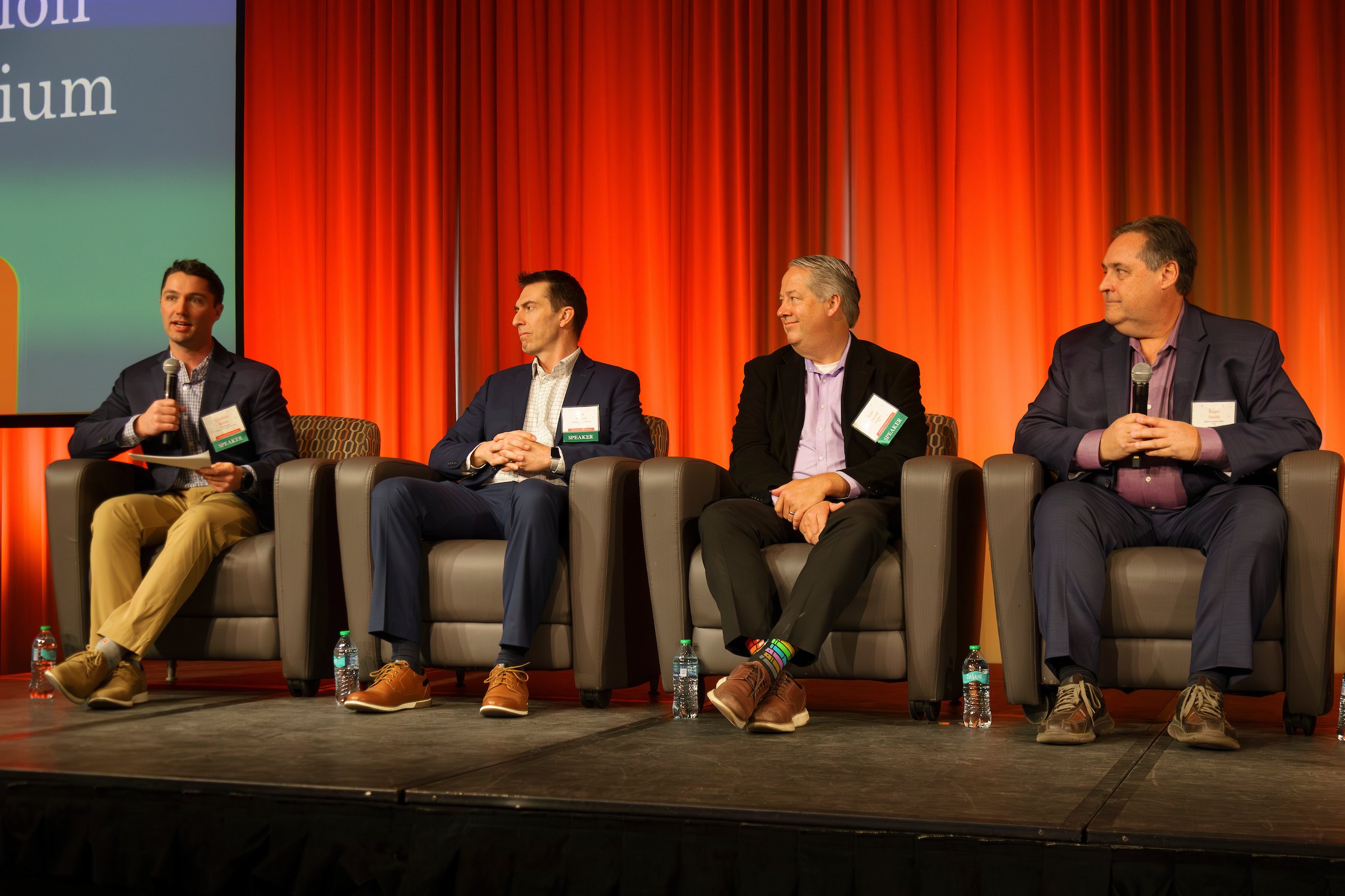 Four people sit on a stage during a conference.