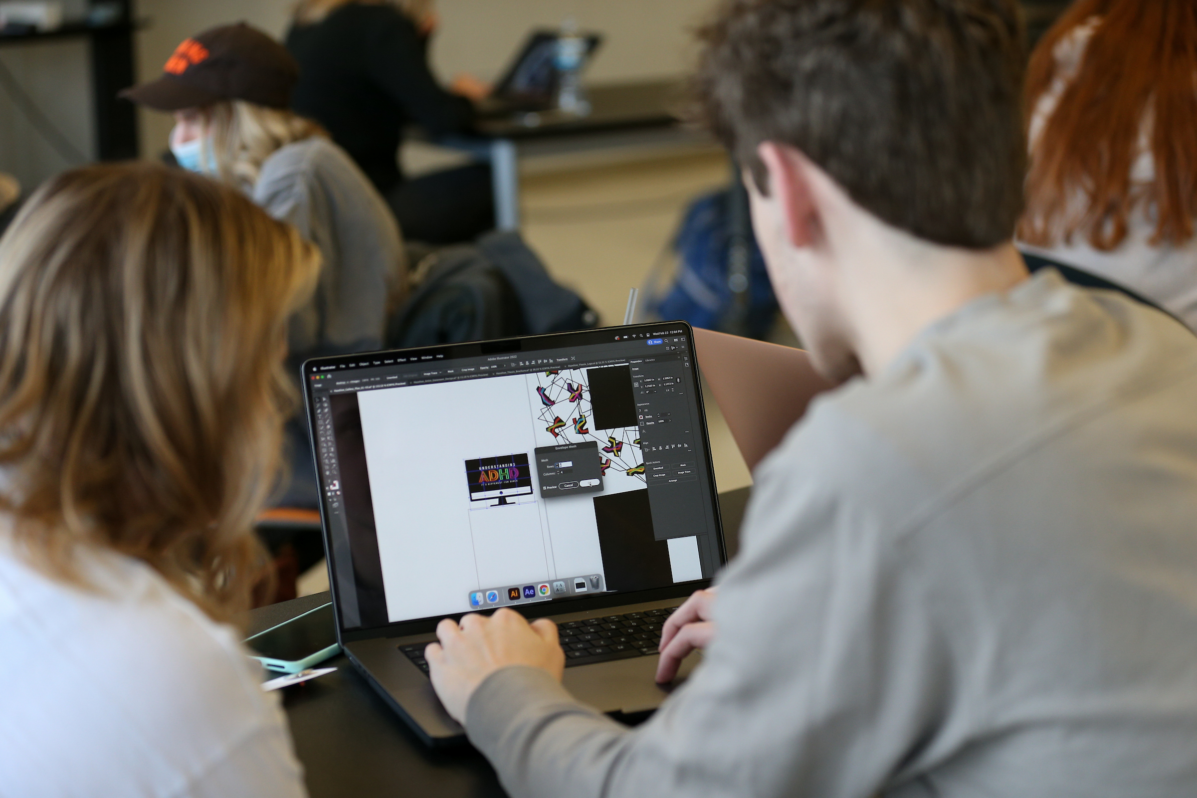  Two students work at a laptop.