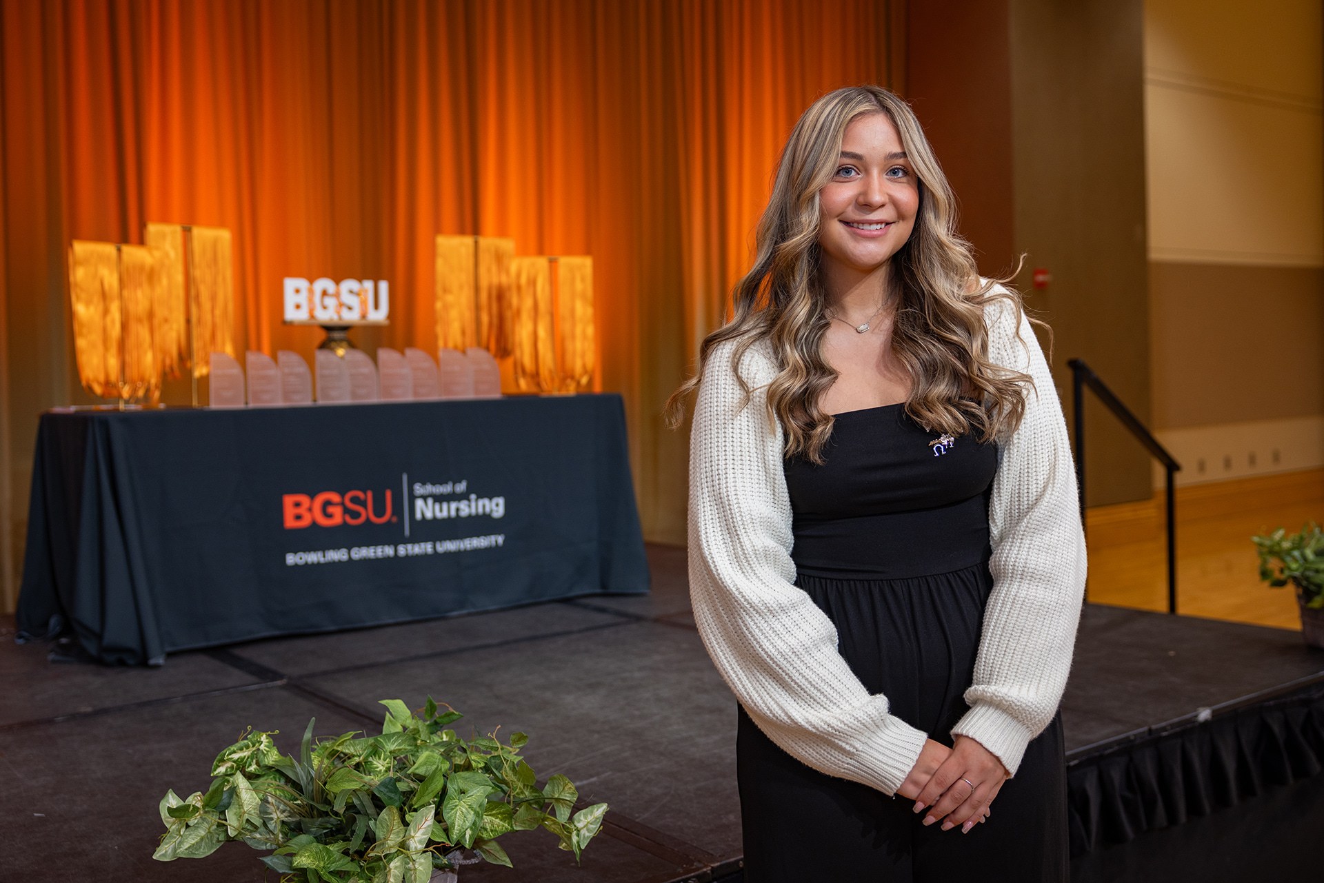 A student poses in front of a branded backdrop.