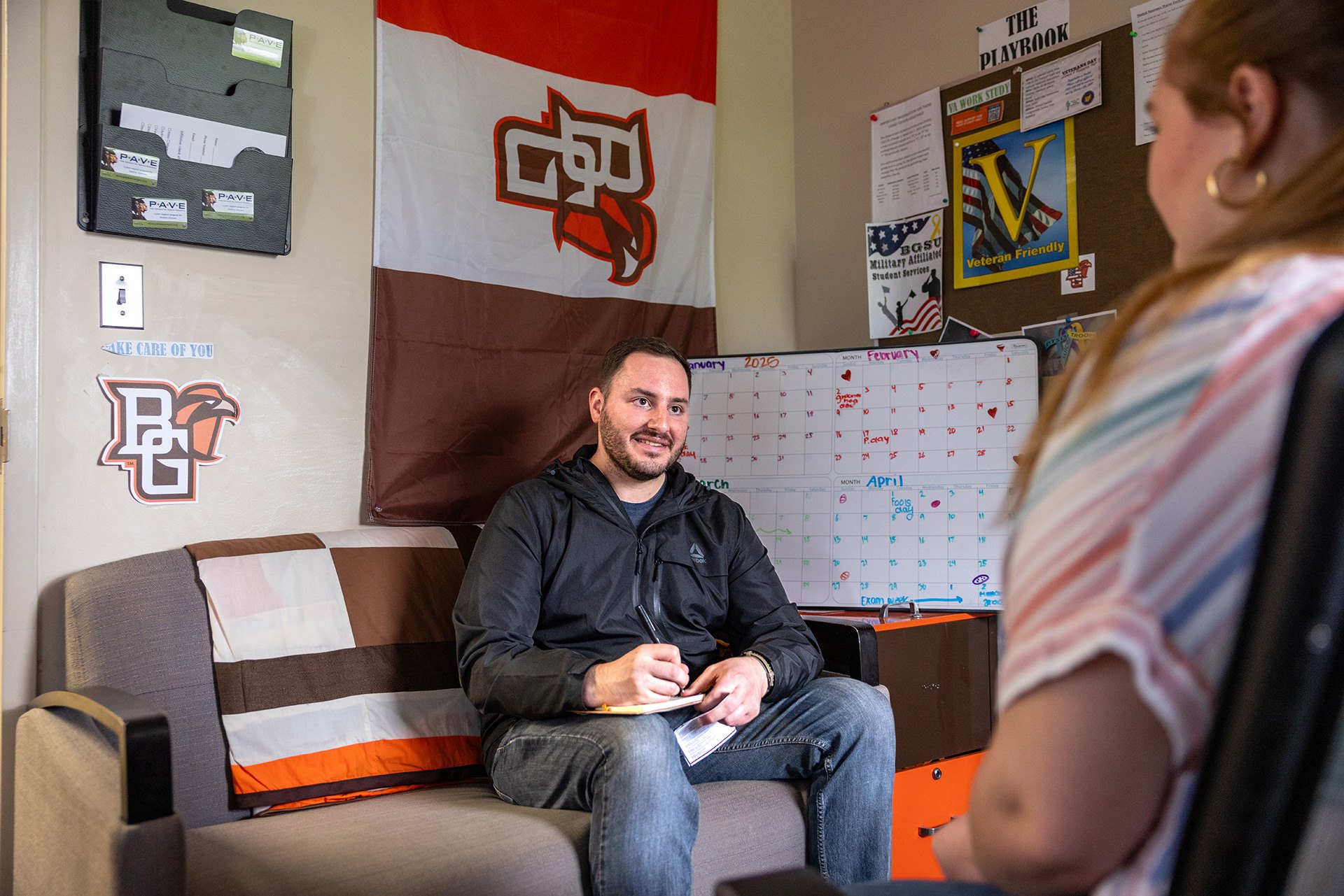 A person counsels a student while sitting on a couch