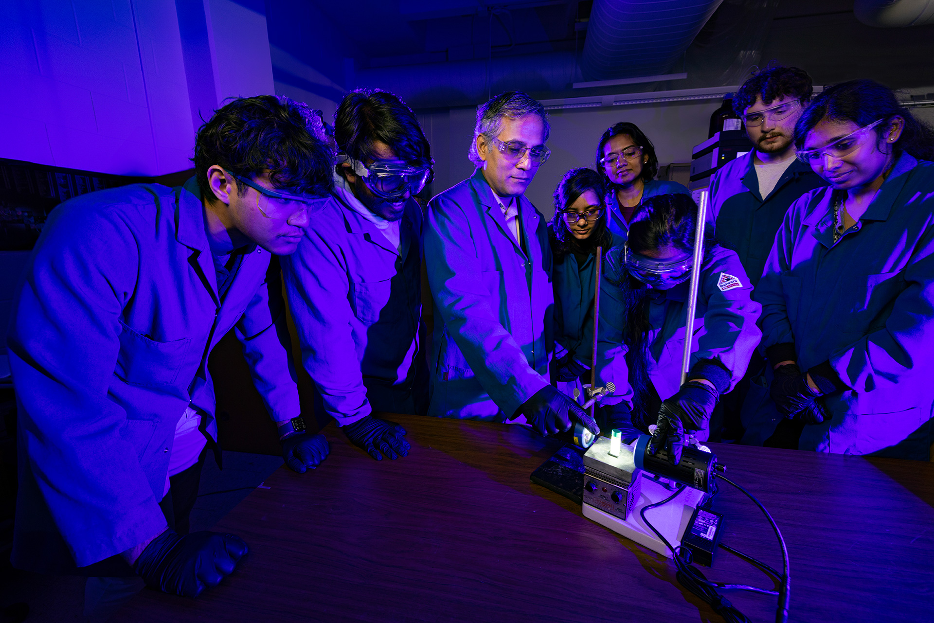 Students surround a professor in a lab