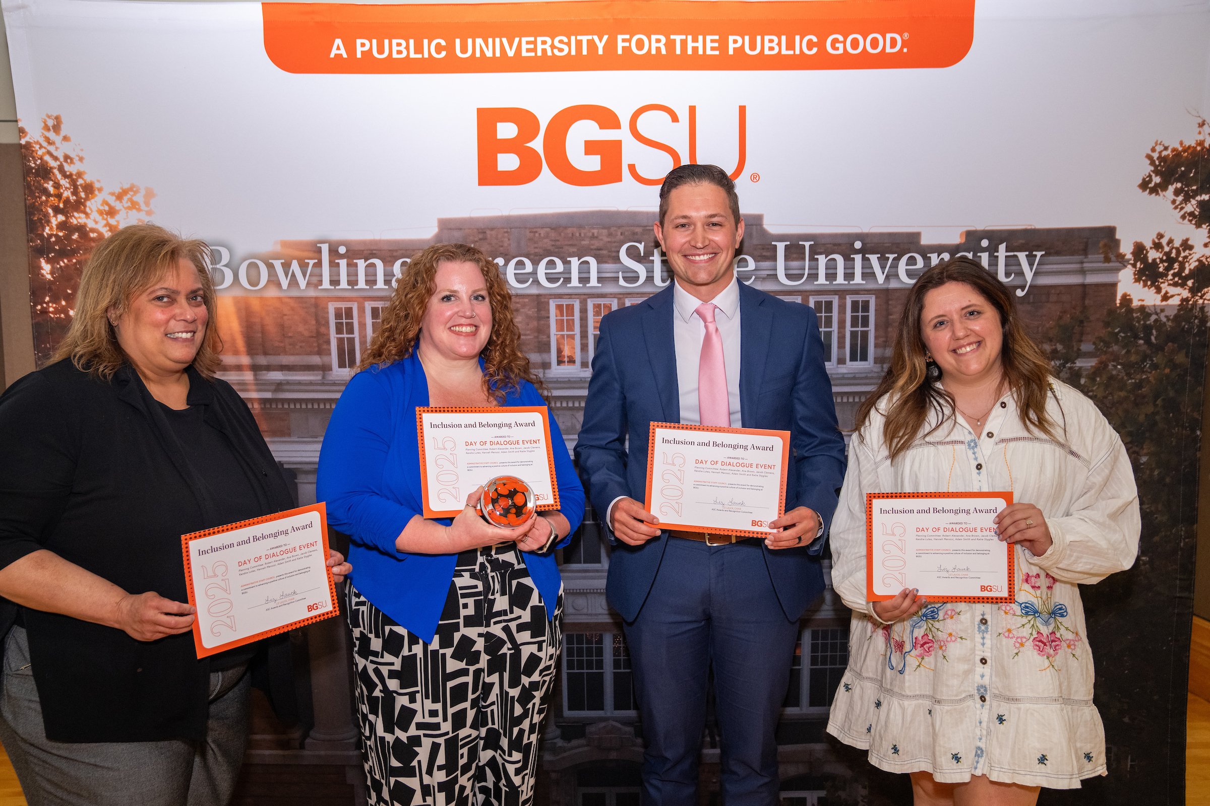 Four people hold awards