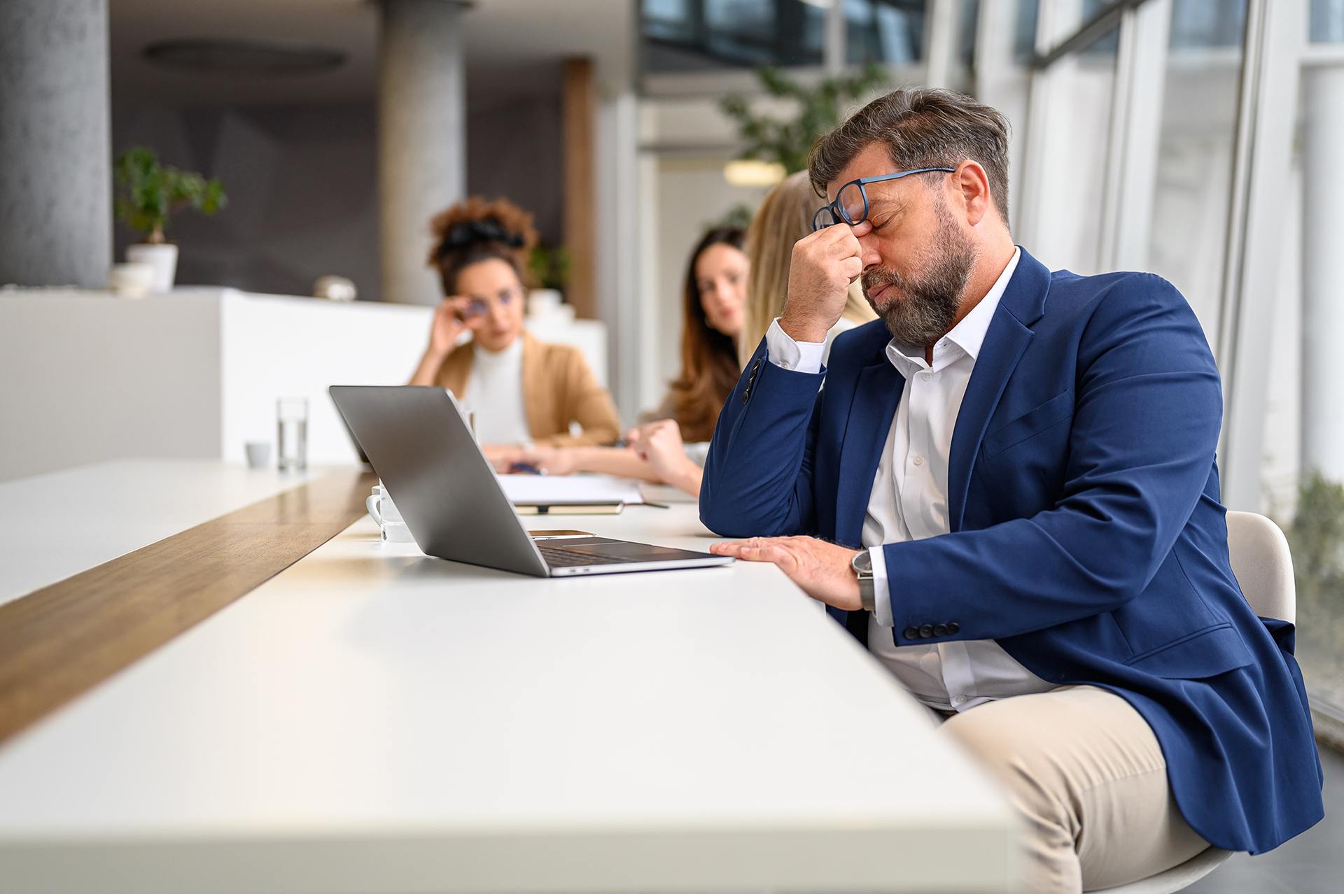 A person sits in a meeting looking stressed