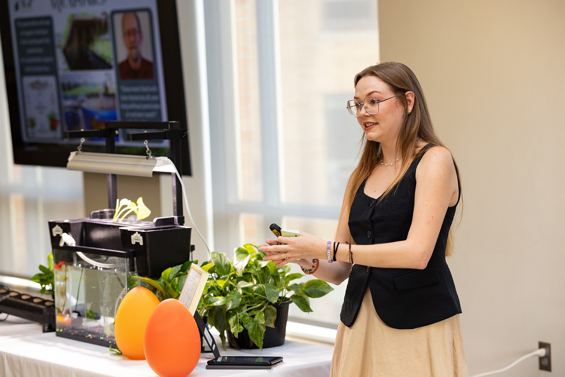 A woman presents next to an aquaponics aquarium