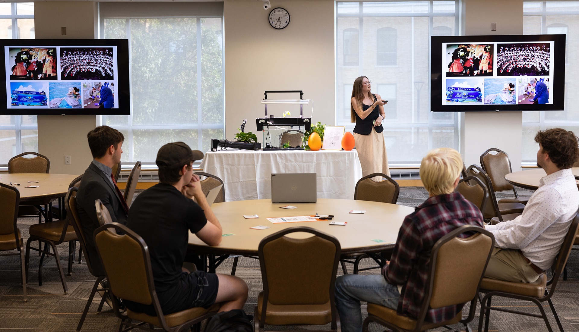 A room full of people listen to a presenter
