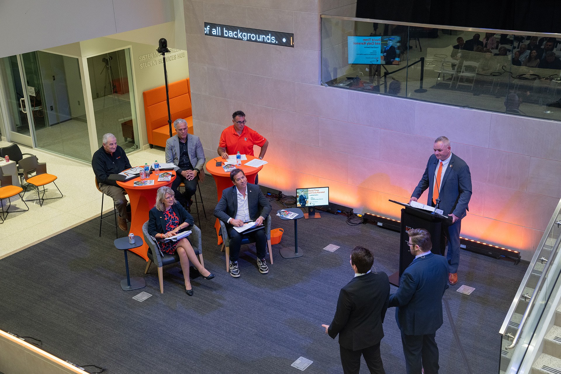 Two people stand on a stage presenting to a group of investors
