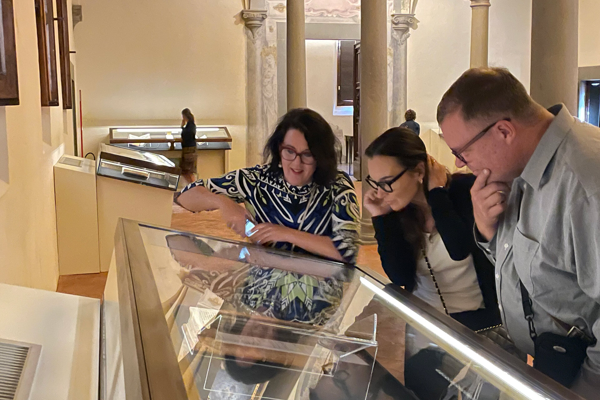 Three people look at a display case