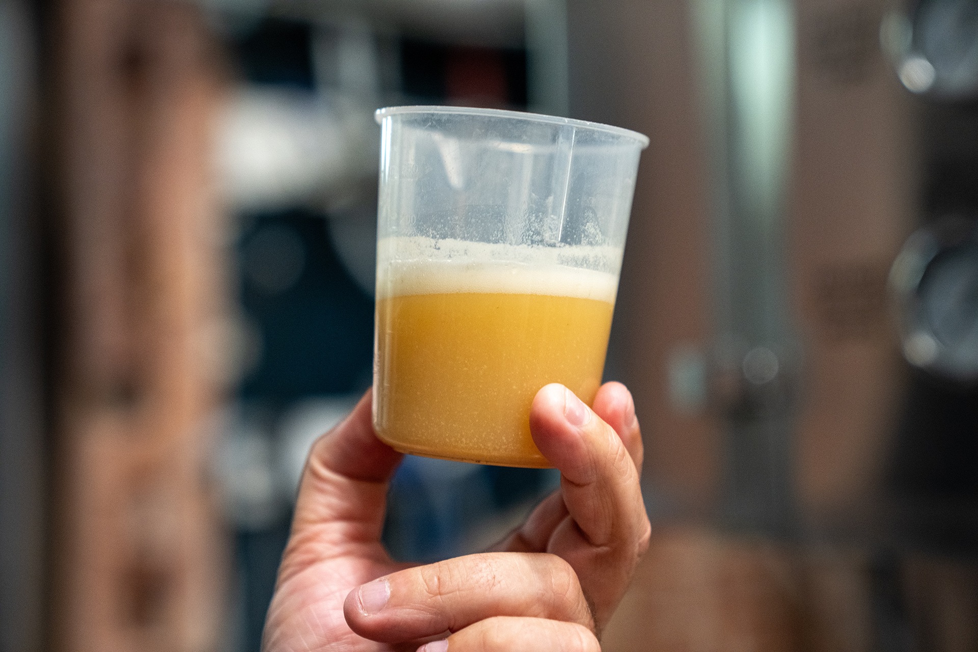 A man holds up a cup of beer.