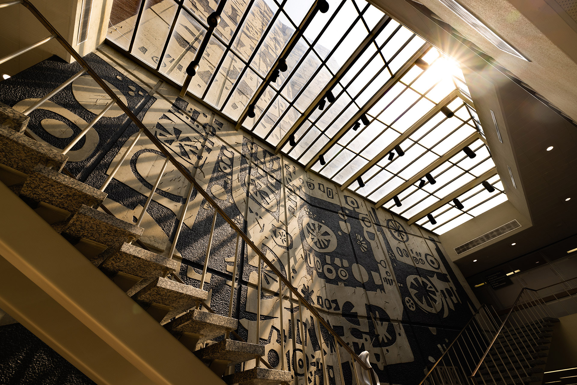 A mural inside a building can be seen through glass windows