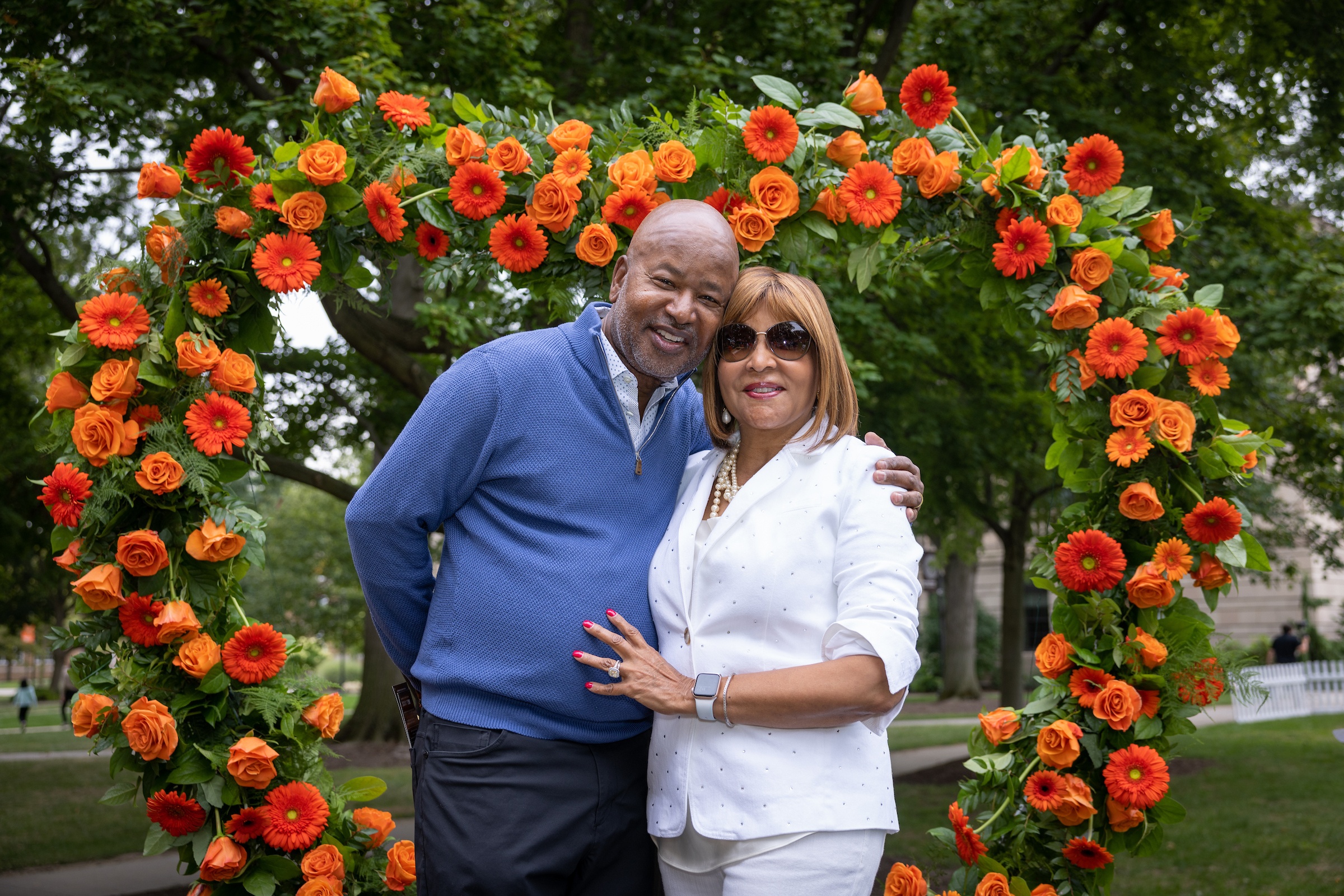 Two people stand in front of a heart-shaped arch