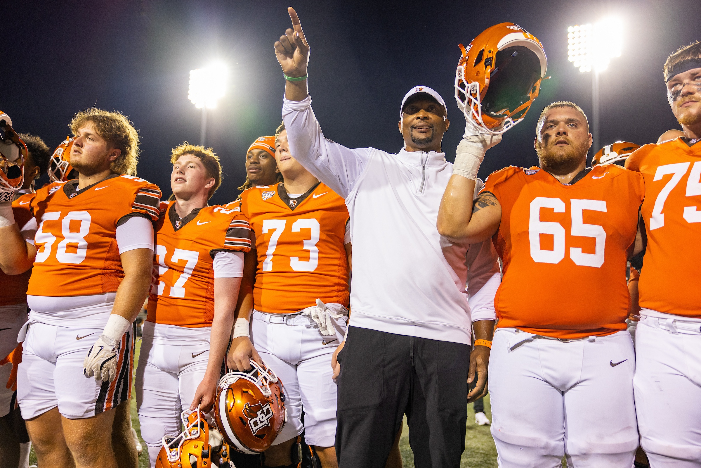 Coach Eddie George flanked by football players