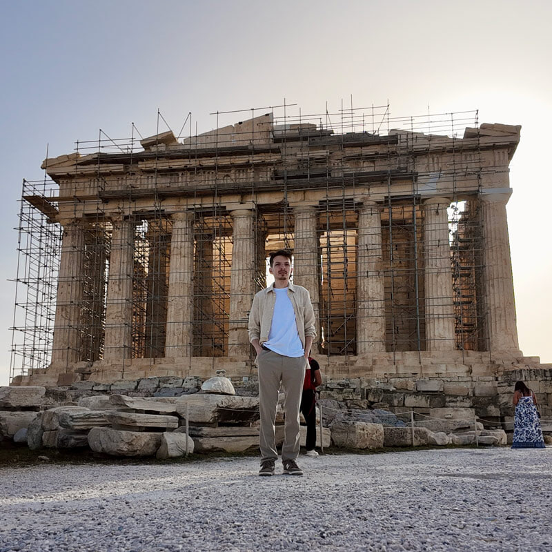 A person poses for a picture in front of the Parthenon in Athens, Greece