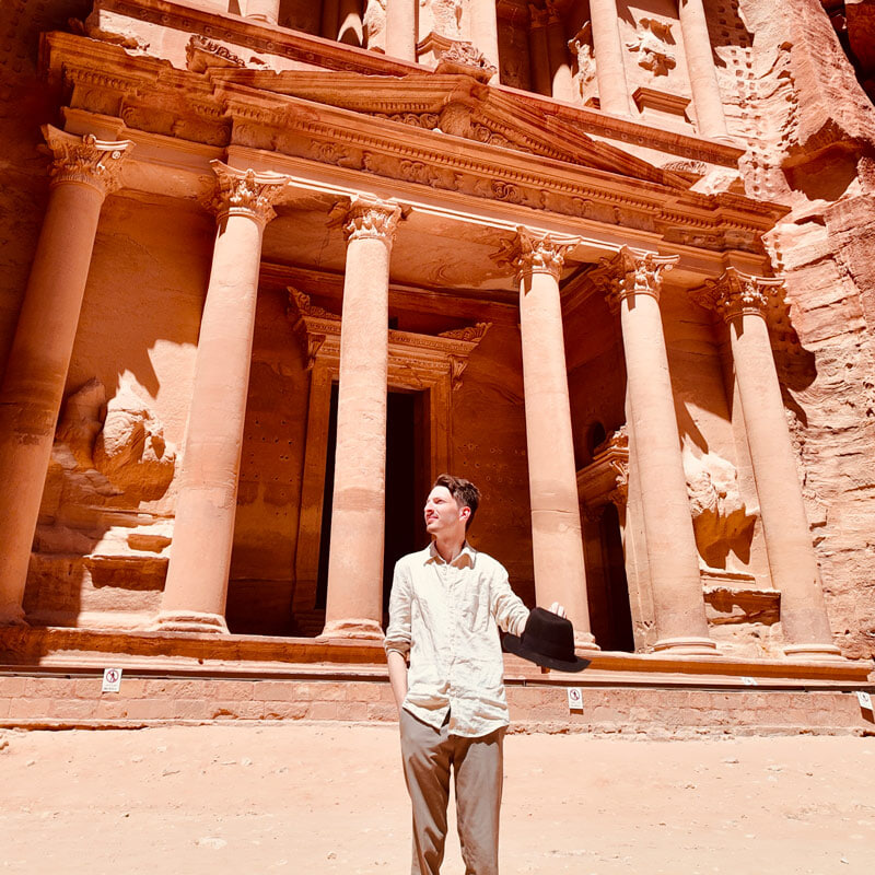 A person poses for a picture in front of the ancient city of Petra, Jordan