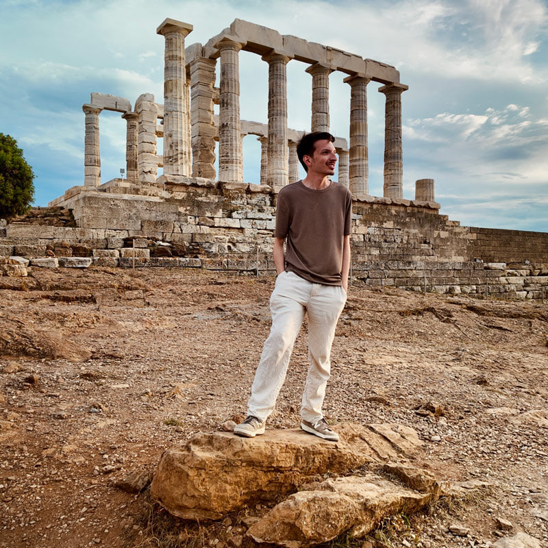 A person stands in front of the Temple of Poseidon in Athens, Greece