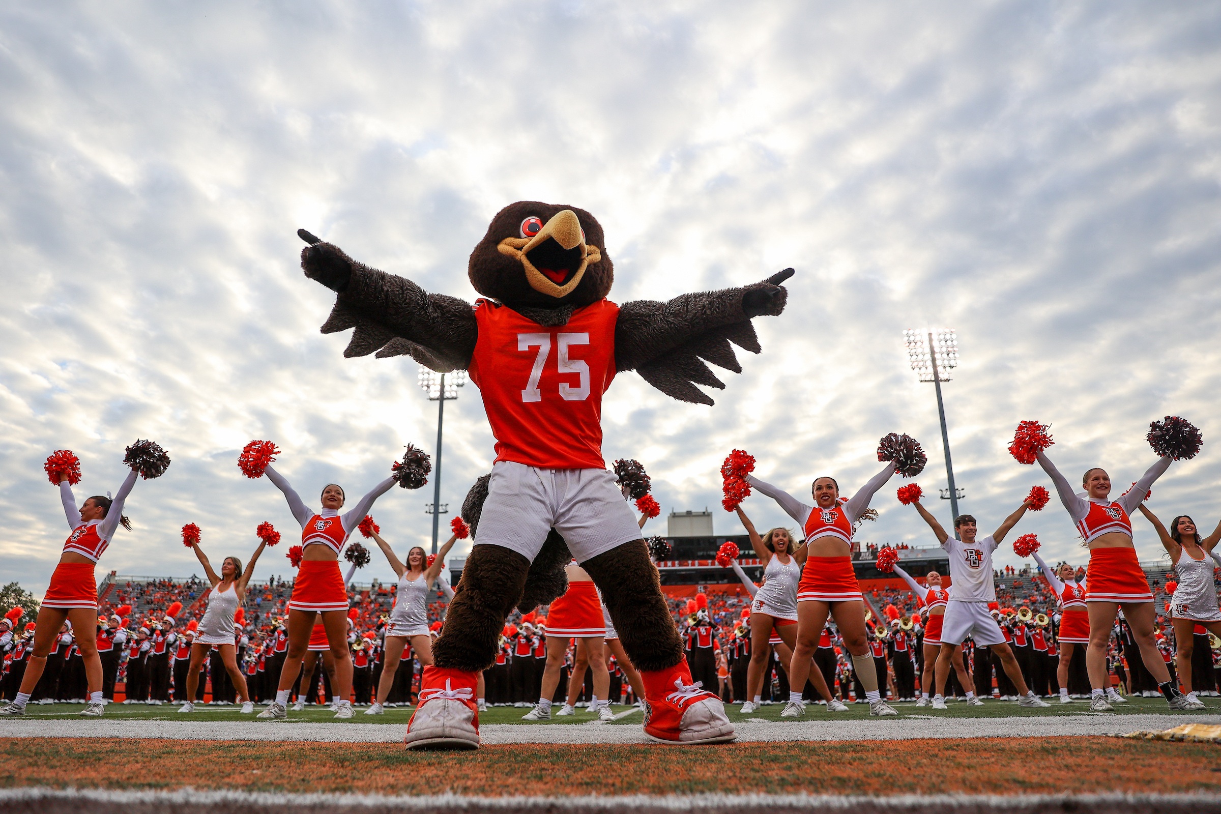 Freddie Falcon on the field with the band and cheer team