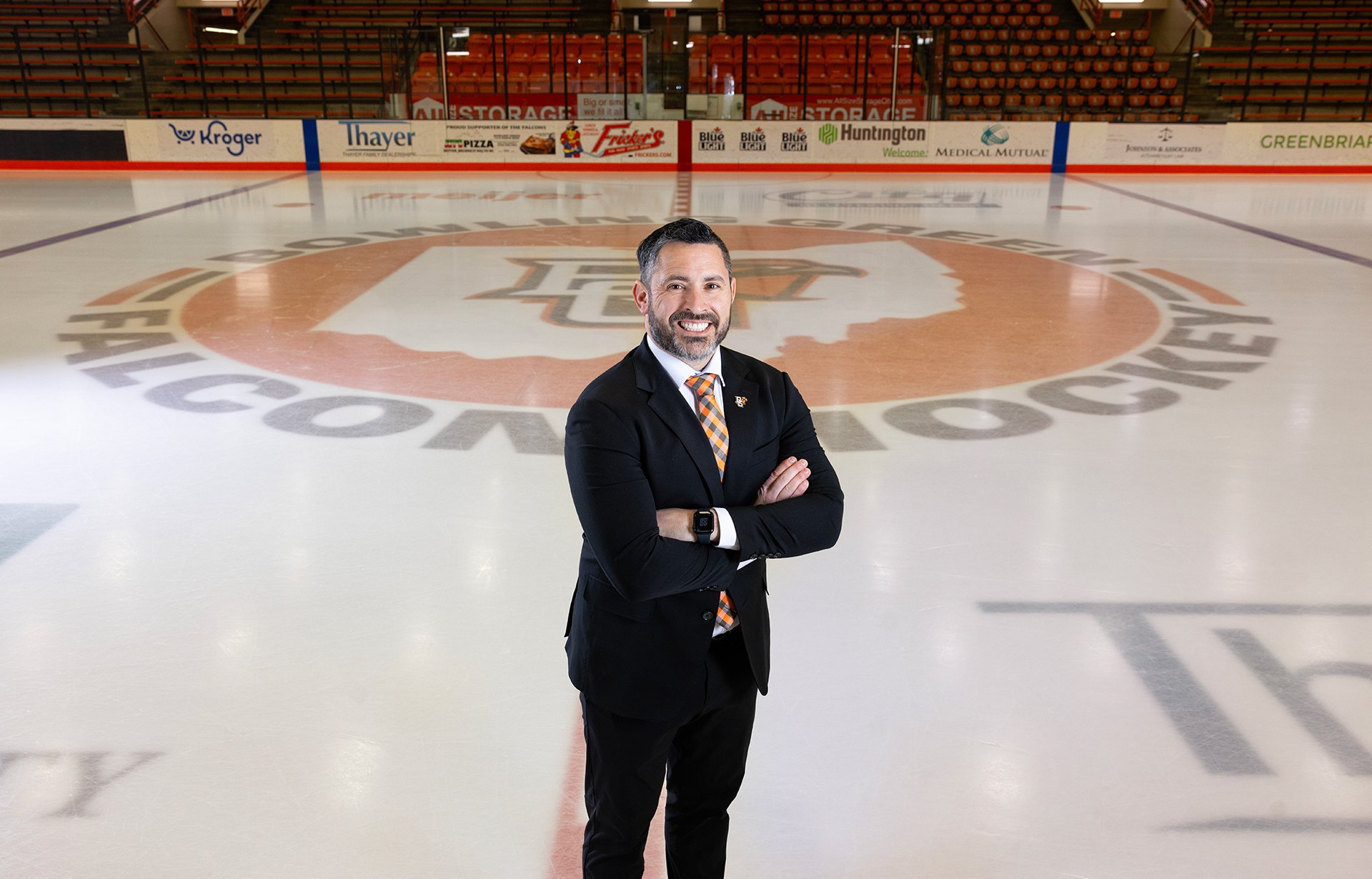A hockey coach poses at a rink.