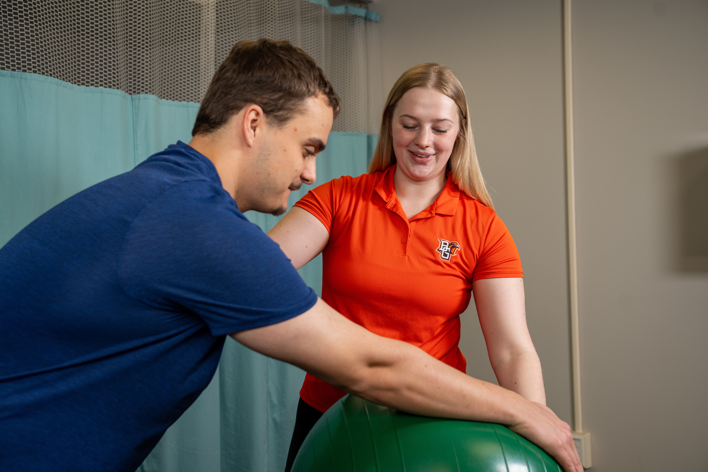 A person helps a patient use an exercise ball