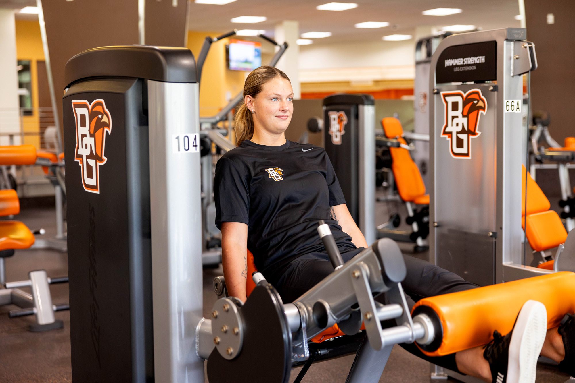 female student lifting quads on machine