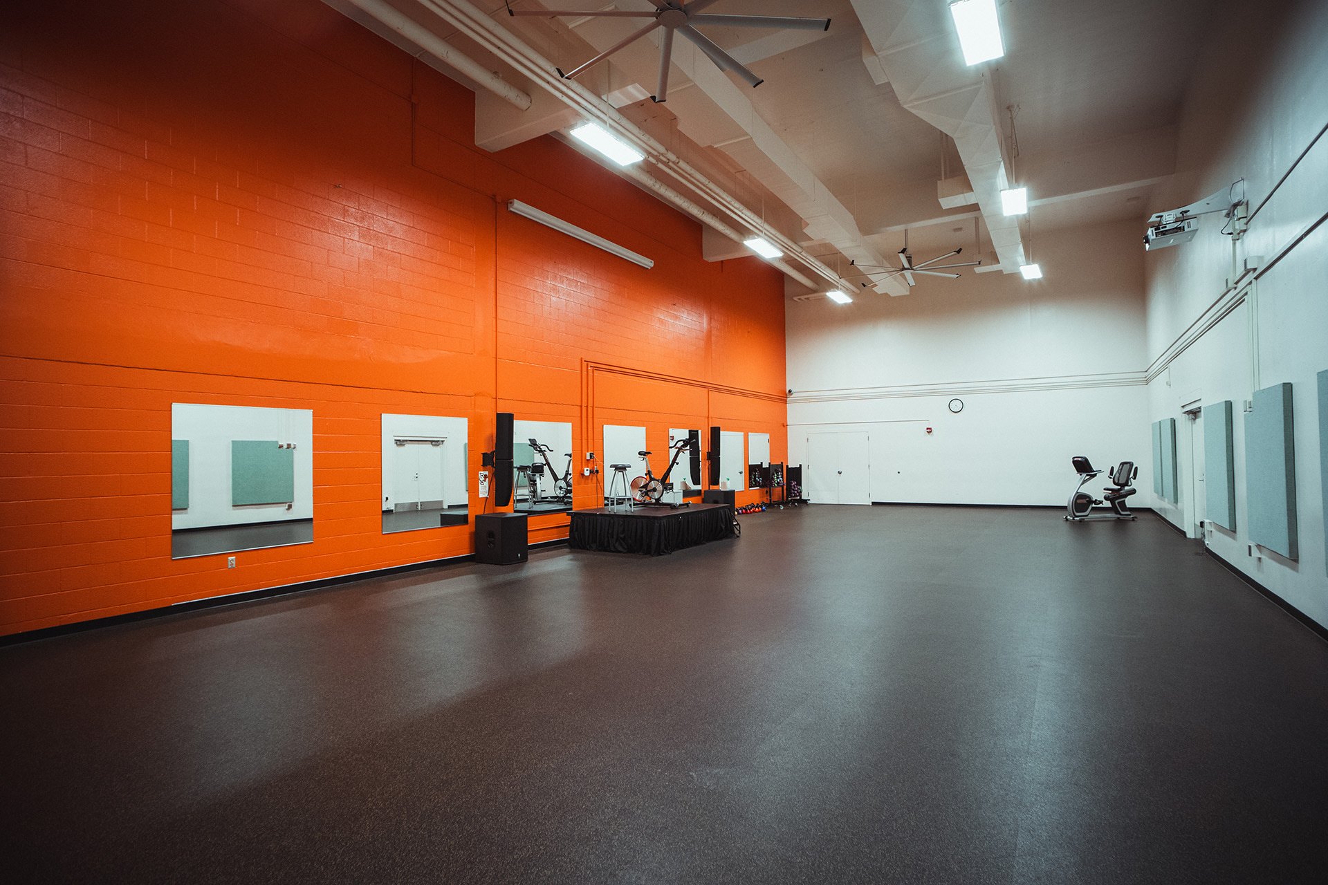 Studio A fitness room with rubber floors and a small stage setup for spin class