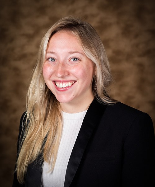 Jessica Patton, in formal attire, in front of a brown background.