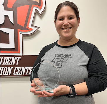 Ashley Hartman holding a round glass award plaque.