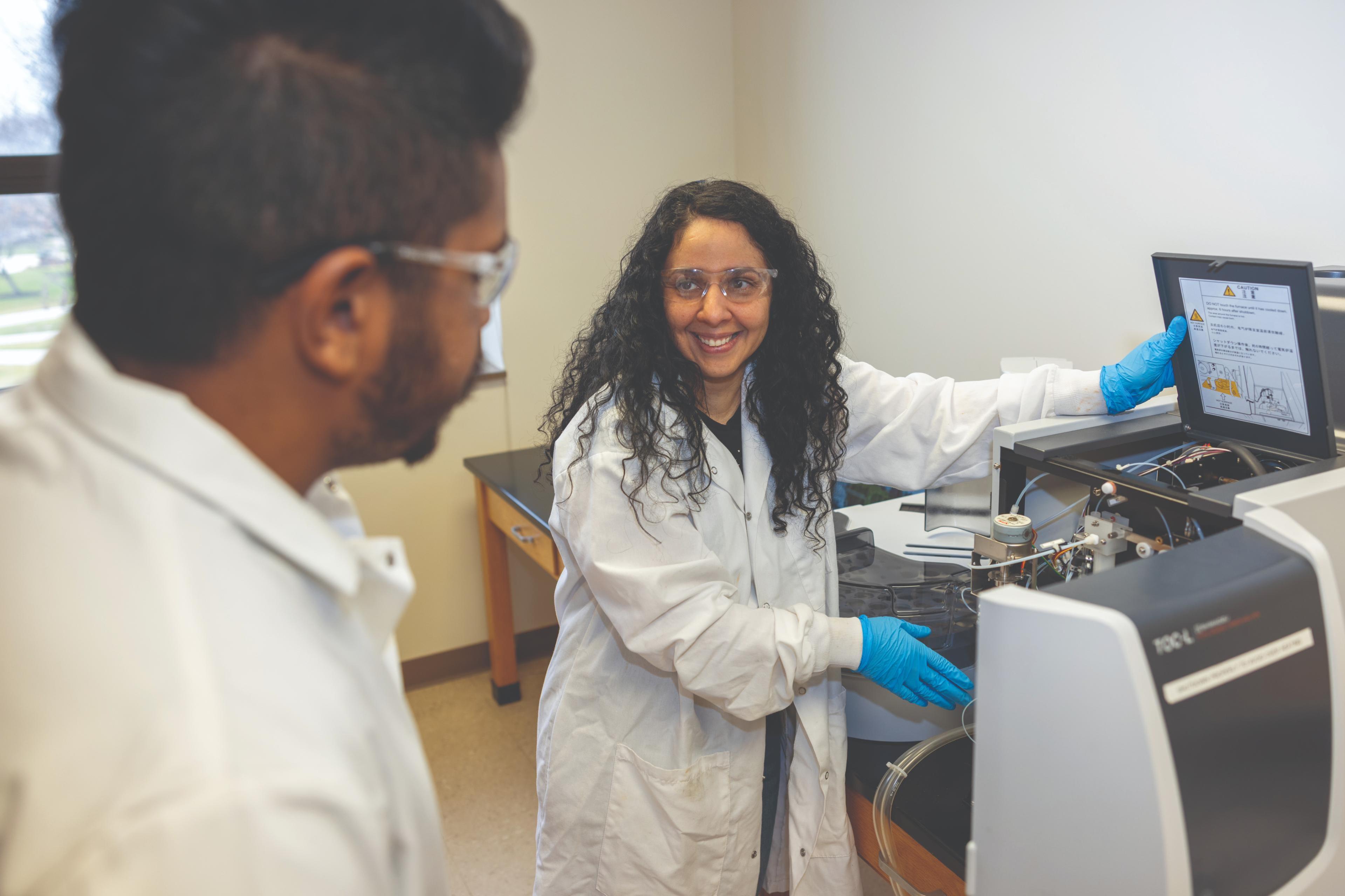 A faculty member demonstrates equipment in the Aqueous and Terrestrial Geochemistry Lab