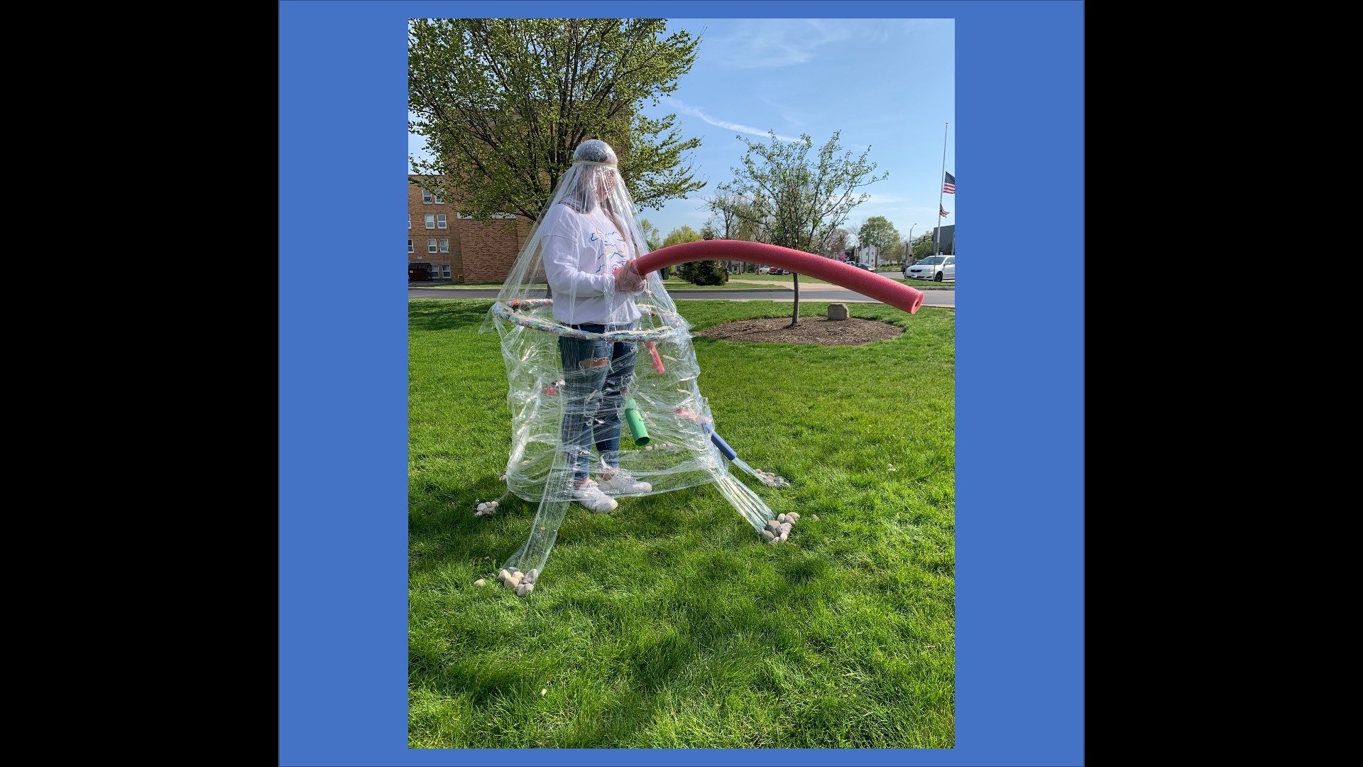 outside photo of figure wearing of plastic tent structure with swimming noodles