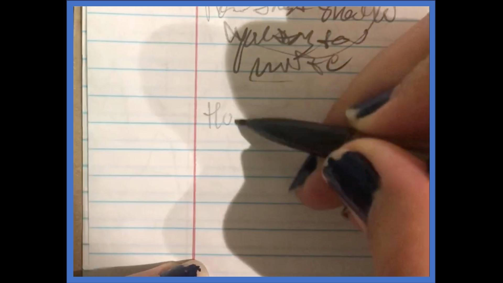 close-up of hand holding pencil and writing on lined paper