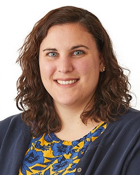 This is a picture of Sarah Joslyn. She has shoulder-length wavy hair. She is standing against a white background.